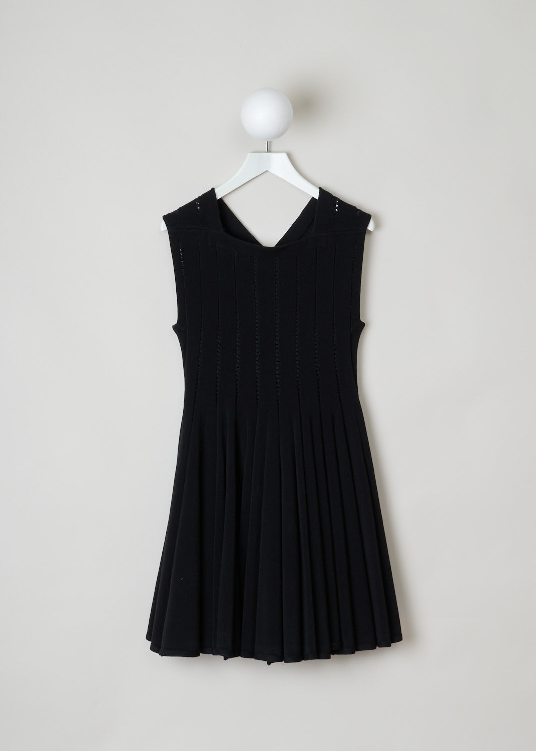 ALAÏA, Black embroidered babydoll dress, 4W9RB20CM120_baby_doll_SM_noir_C999, Black, Front, This black babydoll dress features a square cut neckline in the front and a V-shape in the back. The dress is put together in strips of fabric connected by black embroidery. The skirt is designed with knife pleats and flares out. The dress is thigh high. In the back, a concealed zipper functions as the closure.
