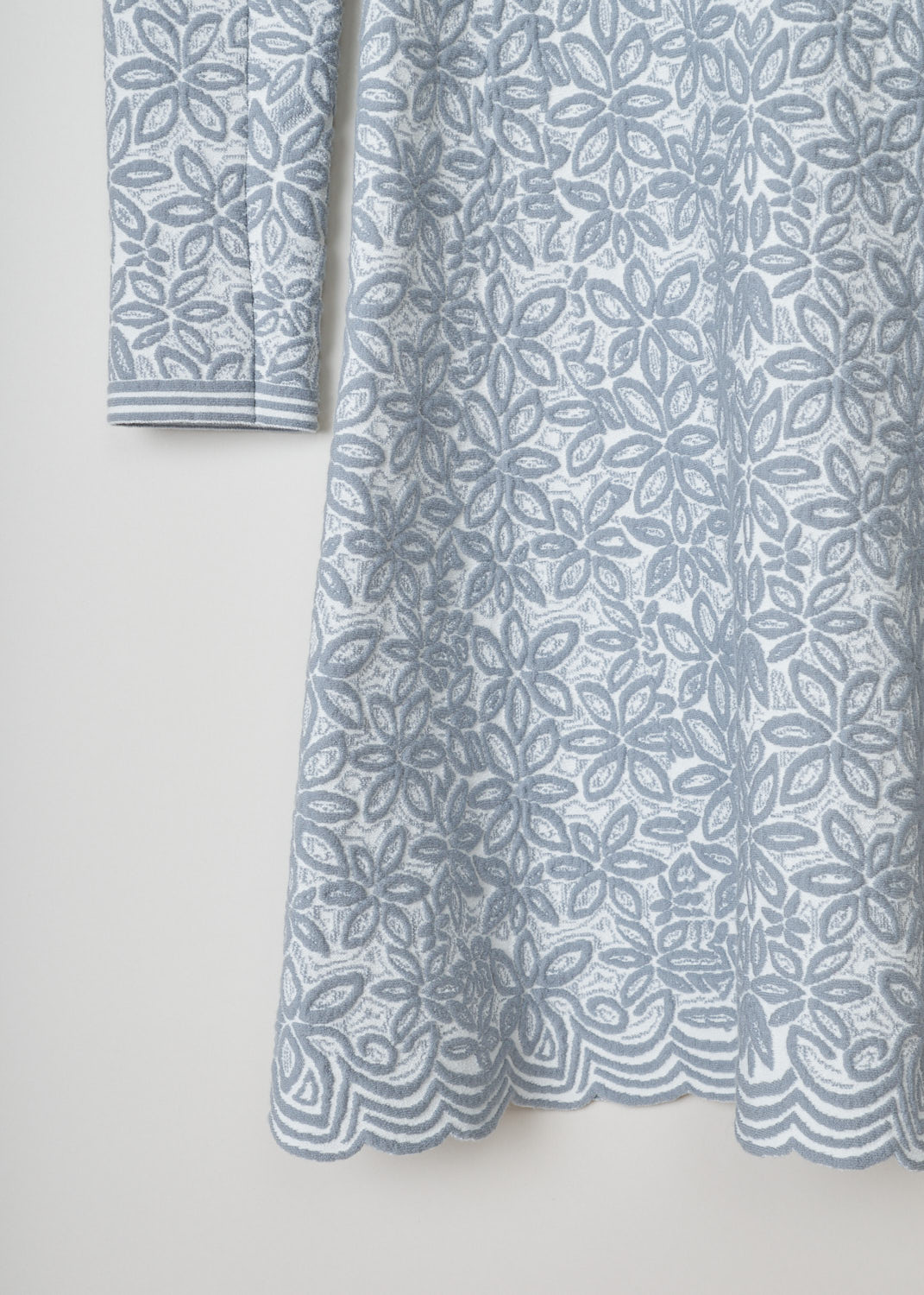 ALAÏA, Grey floral princess dress, 7W9RI74CM353_robe_ml_courte_adenium_C051_blanc_gris, Grey, Print, Detail, This grey mid-length dress has a leafy print throughout. The dress features a scoop neckline and long sleeves. The dress has a fitted bodice and the skirt flares out. A concealed zipper can be found in the back. 
