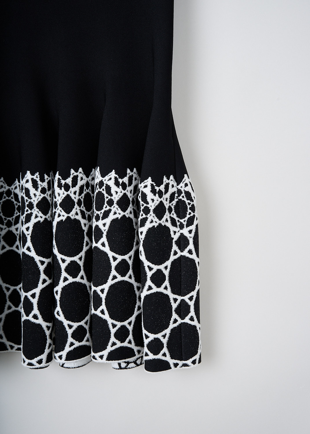 Alaïa, Black fitted dress with diamond-print, AA9R2168CM634_991_NOIR_BLANC, Black, White, Print, Detail, This black midi dress has a scoop-neckline and short sleeves. The dress has a fitted bodice with a flared skirt. The hem of the skirt has a diamond-like print in white.
