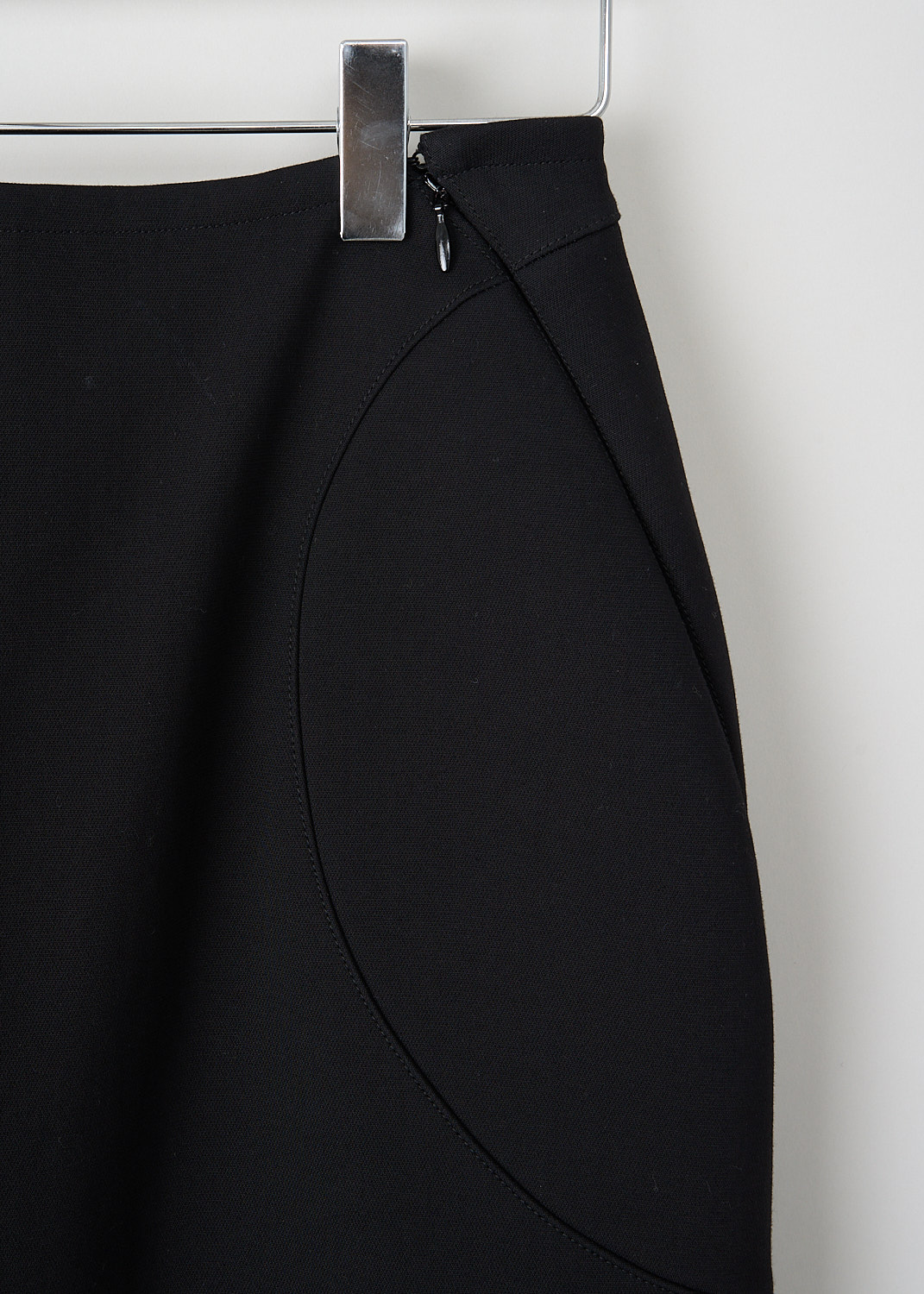 Alaïa, Black pencil skirt with padded inserts, AA9J05215T621_995_NOIR_ALAIA, Black, Detail, This black midi pencil skirt has padded inserts on the front and back. A concealed zip runs diagonally from the front into the side seam. In thee back, the skirt has two concealed zips that can functions as slits.
