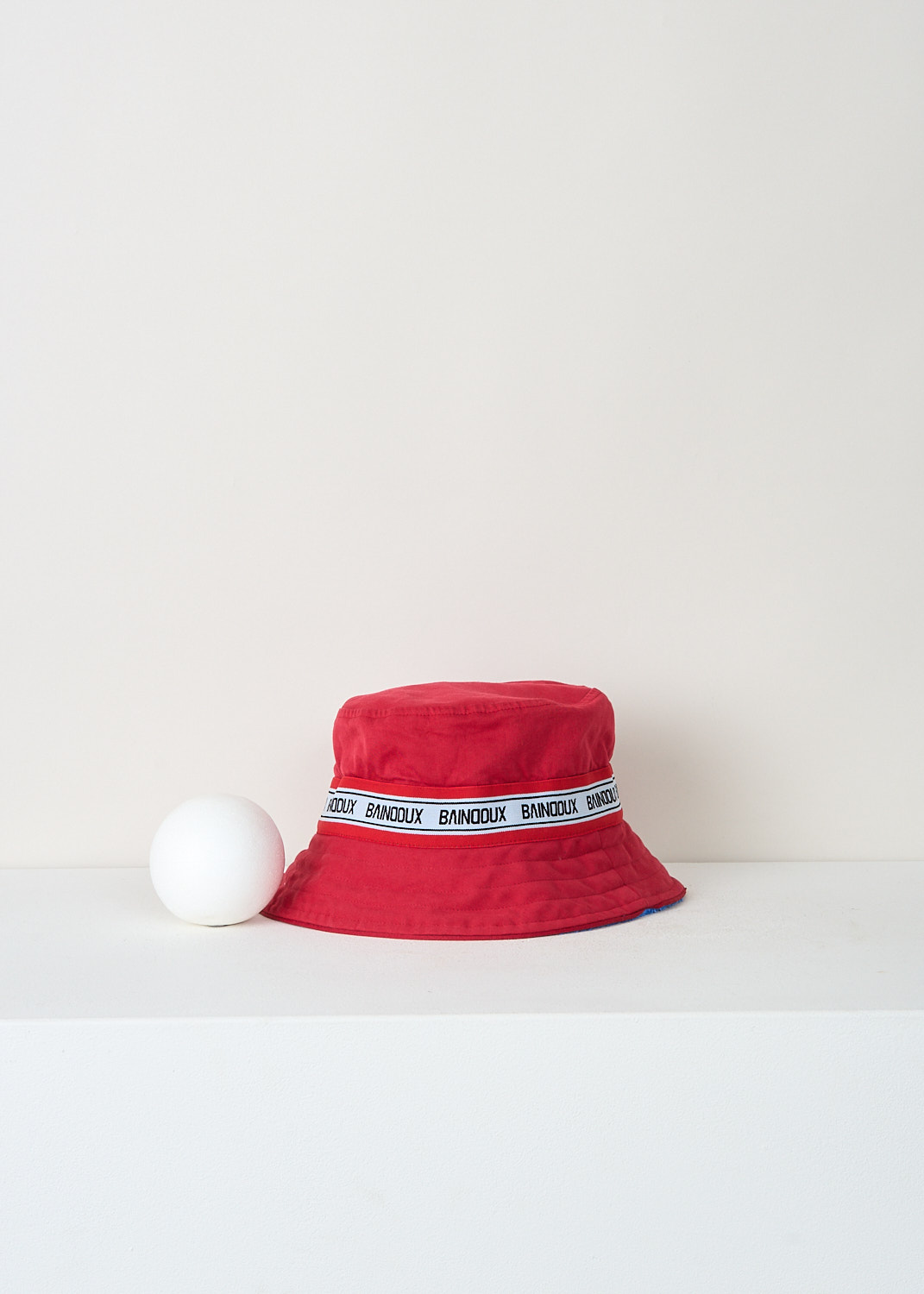 Baindoux reversible red terrycloth bucket hat with off-white grosgrain ribbon and black logo lettering, 100% Giza cotton designer accessory at Kiki Niesten Maastricht