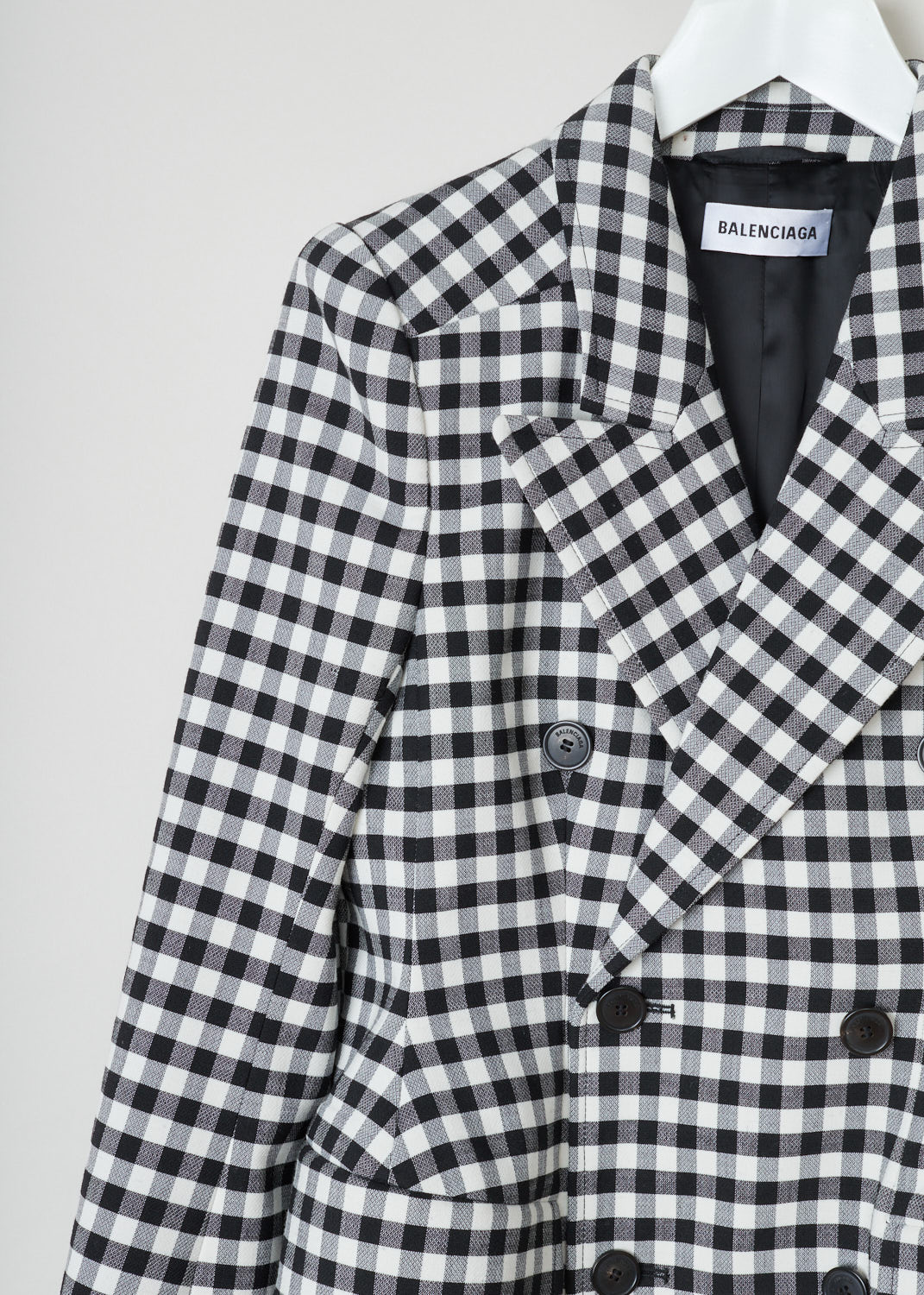 Balenciaga, Checkered double breasted blazer, 479866_TDT10_1070, black white, detail. Black and white checkered jacket, double breasted model with regular collar and peak lapels. Accent on the waist due to padded hip parts. Long cuffed sleeves with four buttons. Comes with two flap pockets on the front.