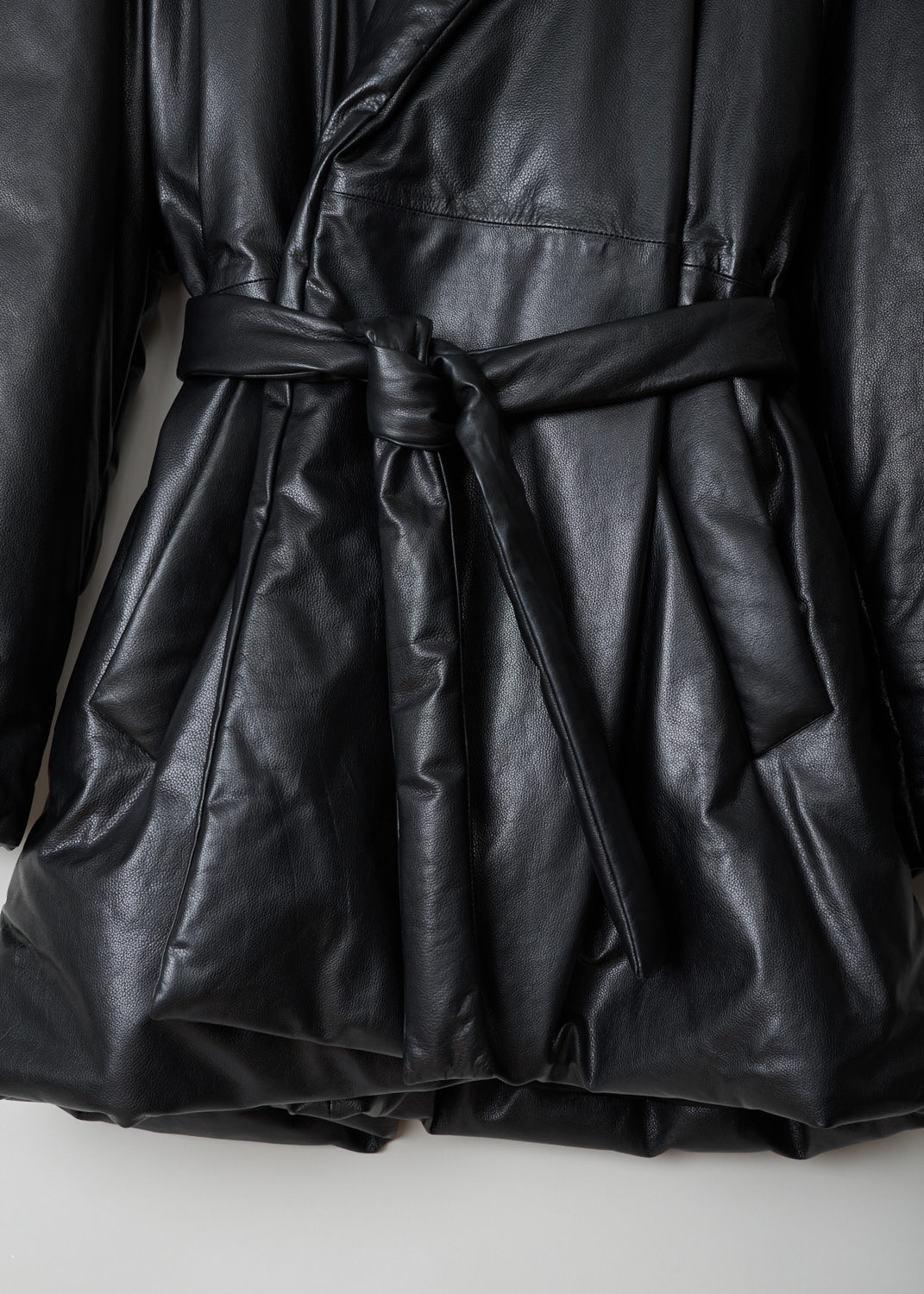 Balenciaga, Black lined leather coat, 583549_TFS06_1000, black, detail. Lovely black quilted, calfskin coat made by true craftsmen. Featuring a collar that leads into the notched lapel, which leads into the fastening option being, waist-tie ribbon made from the same fabric. Comes with dropped shoulders and long sleeves. Furthermore two welt pocket can be found on the front and two more slip-in pockets on the inside.  