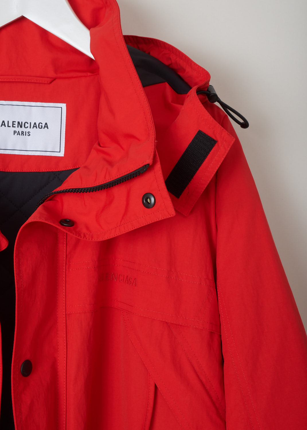 Balenciaga, Red parka model, 646774_TJ014_6400, red, detail1. Red oversized parka has lots of features beginning with the hood which is lined and detachable with press buttons. Going down this model has 4 pockets 2 on chest height 2 below that, with al the pockets being forward slanted. There is a cord tunnel on the inside with which the width of the waist can be adjusted. The fun part of this parka is the zipper which starts from the sides going up to the armpit and ending on the sleeves. Comes with zip fastening 