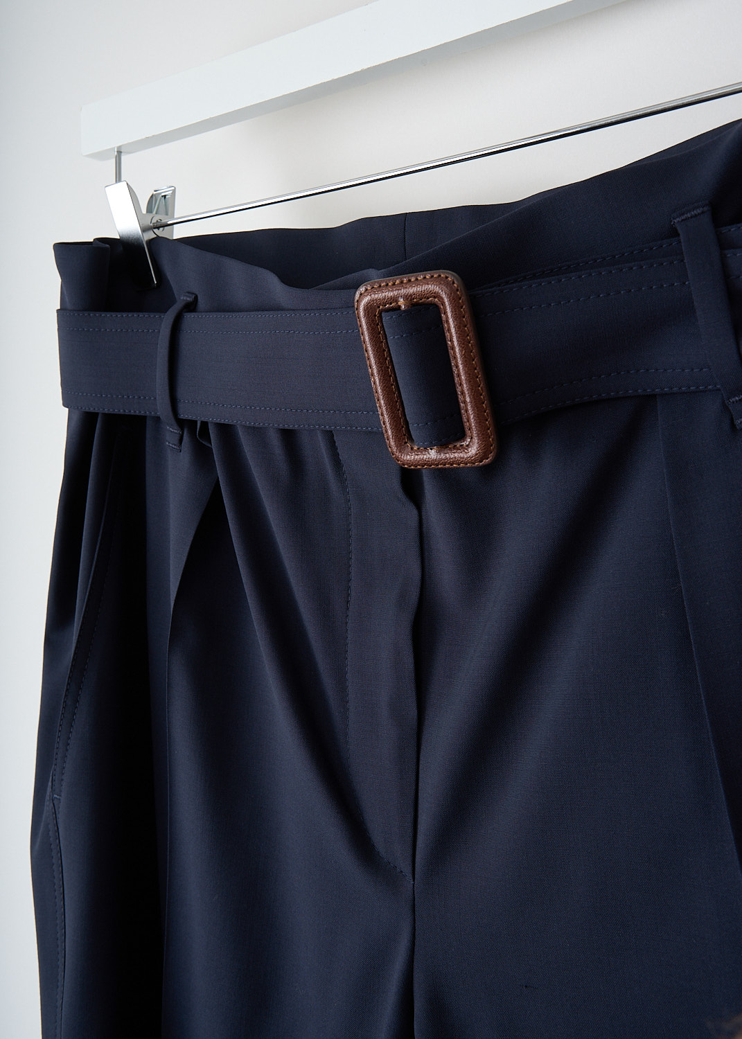 Brunello Cucinelli, Navy blue wool pants with matching belt, MA105P6899_C1359, Blue, Detail, These navy blue wool pants have an elasticated waist, a concealed clasp and zipper closure and a matching fabric belt with a brown leather buckle. These pants have a pleated front and tapered pant legs with centre creases. In the front, slanted pockets can be found. In the back, these pants have welt pockets. 

