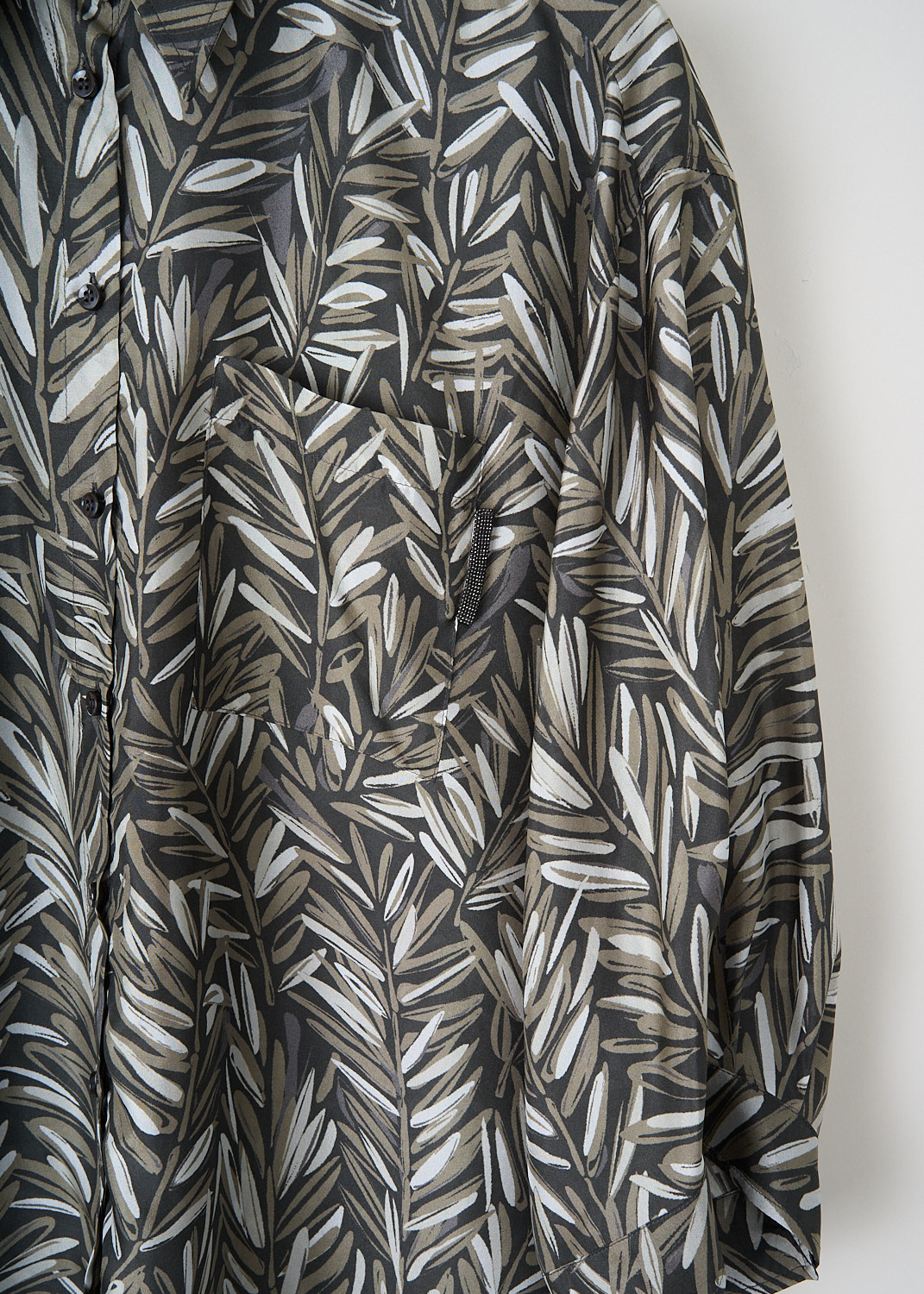 Close-up of Brunello Cucinelli blouse showing green leafy silk print and monili embellishment on the breast pocket.