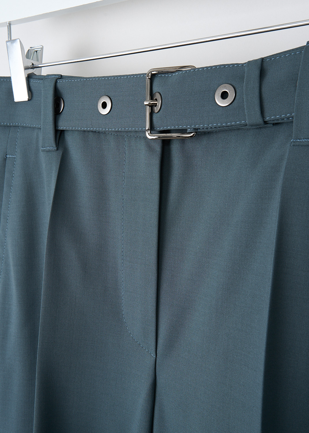Brunello, Cucinelli Green cool wool pants with belt, MP105P7028_C9309, Green, Detail, These mid-rise green cool wool pants have a waistband with belt loops and a concealed clasp and zip closure. These pants come with a matching fabric belt with a silver-tone belt buckle. Slanted pockets can be found in the front. The tapered pants legs have centre creases. In the back, these pants have wel pockets. 
