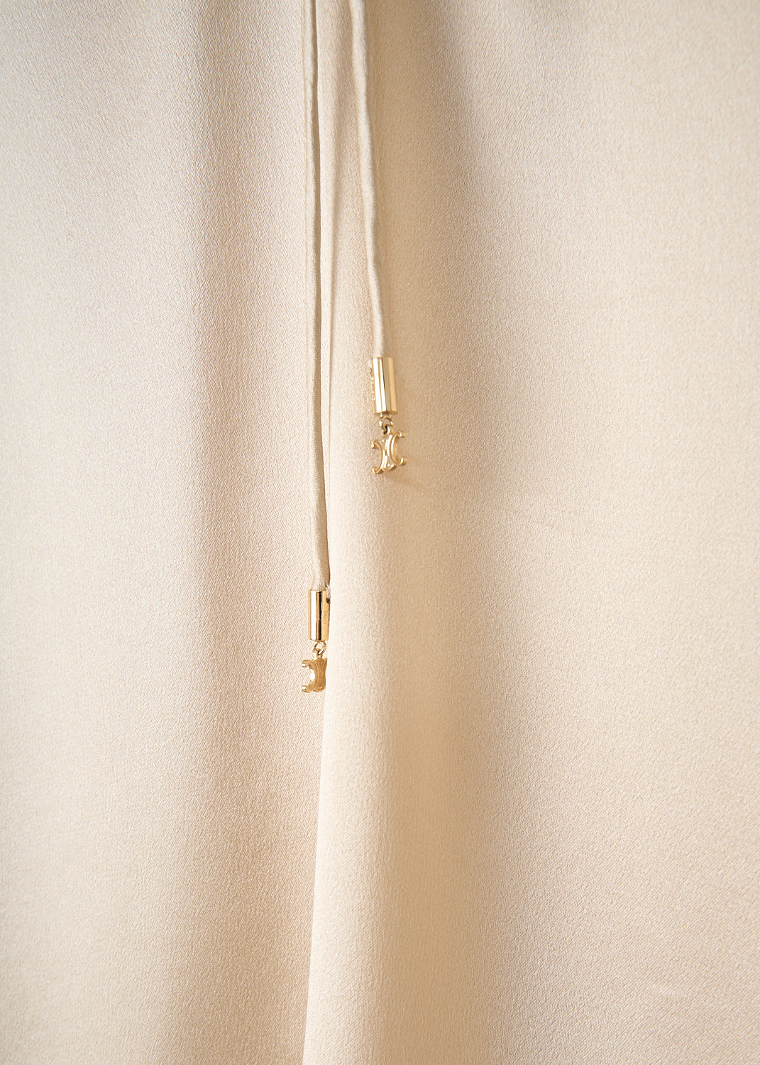 Close-up detail of Celine champagne satin silk blouse showing ruffled V-neckline and tie detail