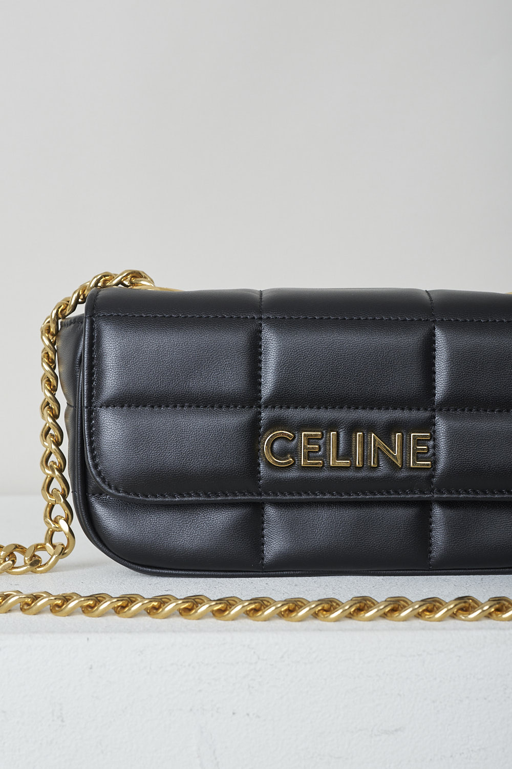 CELINE, BLACK MATELASSÃ‰ MINI CHAIN SHOULDER BAG, 10L333EWJ_38NO, Black, Detail, This black matelassÃ© mini shoulder bag has gold-tone metal hardware with the brand's lettering on the front and a gold chain shoulder strap. The bag has a snap button closure. The flap opens to the main compartment with a inner pocket to the backside.  
