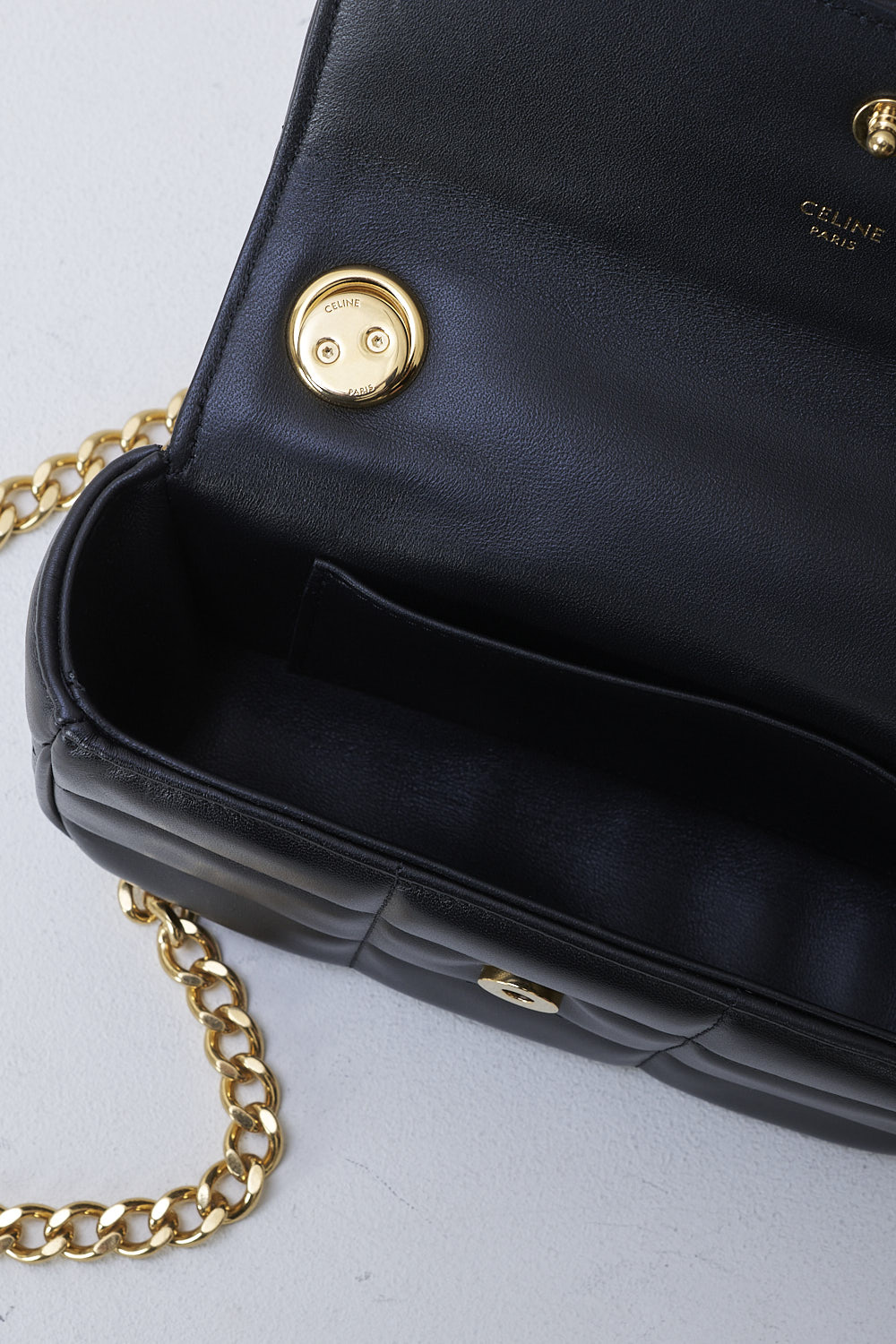 CELINE, BLACK MATELASSÃ‰ MINI CHAIN SHOULDER BAG, 10L333EWJ_38NO, Black, Detail 1, This black matelassÃ© mini shoulder bag has gold-tone metal hardware with the brand's lettering on the front and a gold chain shoulder strap. The bag has a snap button closure. The flap opens to the main compartment with a inner pocket to the backside.  
