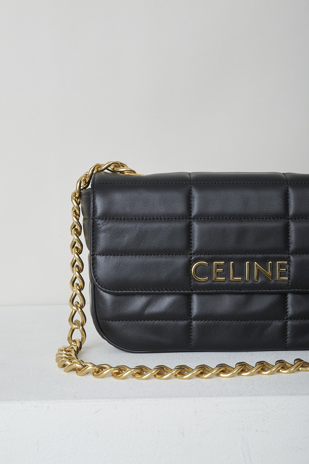 CELINE, BLACK MATELASSÃ‰ SHOULDER BAG WITH GOLD CHAIN, 111273EPZ_38NO, Black, Detail, This black matelassÃ© shoulder bag has gold-tone metal hardware with the brand's lettering on the front and a gold chain shoulder strap. The bag has a snap button closure. The flap opens to the main compartment with a inner pocket to the backside


