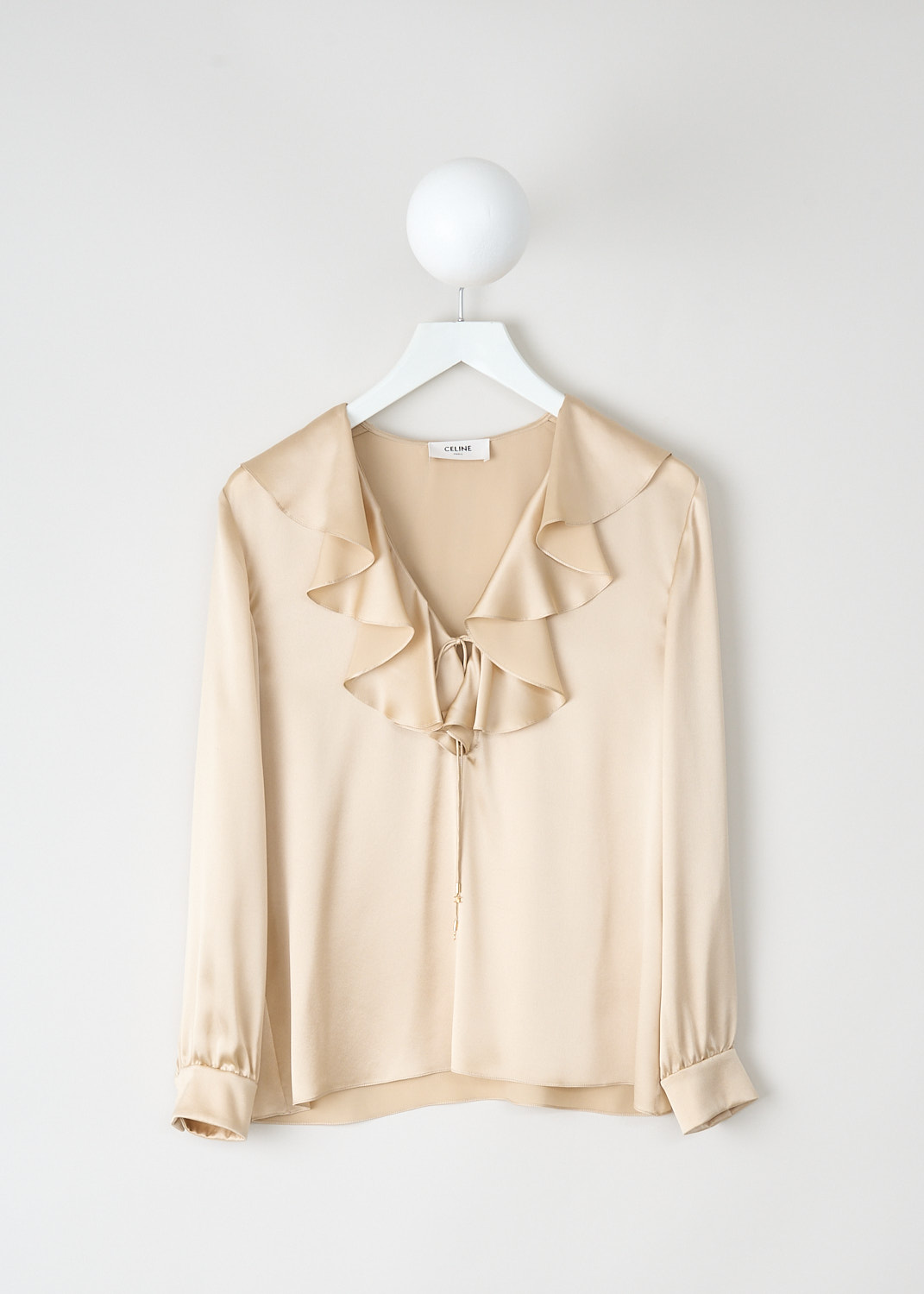 Champagne satin silk Celine blouse with ruffled V-neckline, tie detail, long sleeves with buttoned cuffs and asymmetric hemline, front view, Kiki’s Stocksale Maastricht designer boutique