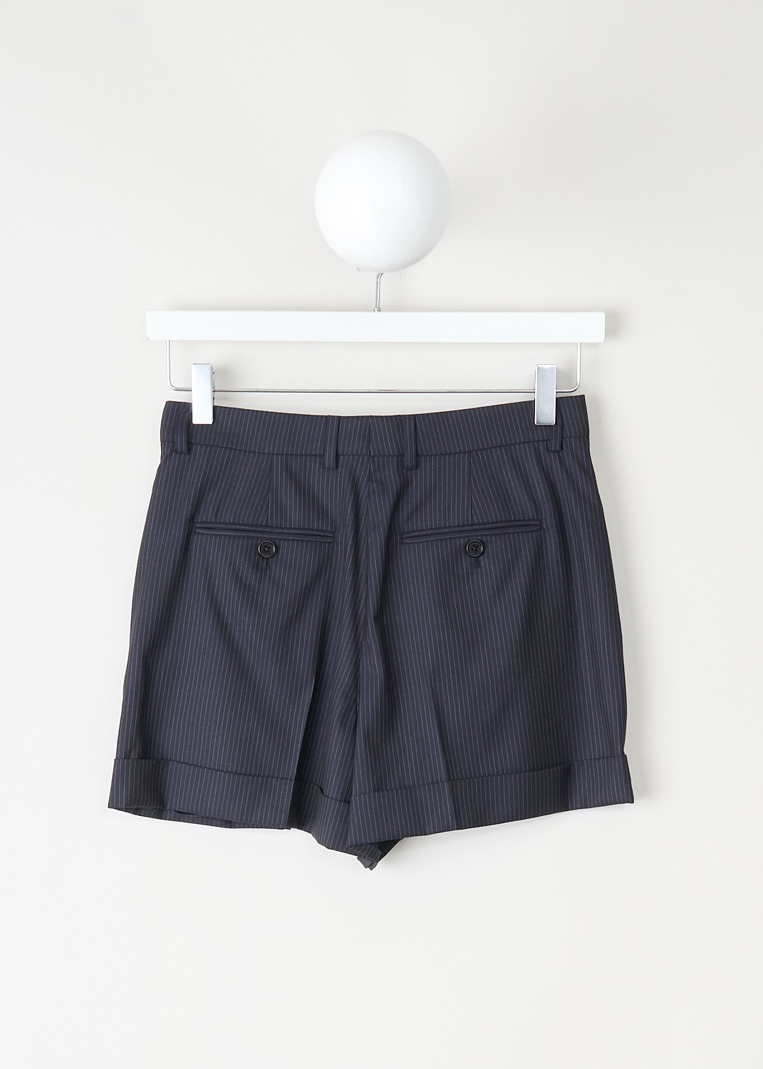 Close-up of navy blue pinstripe wool fabric and tailored waistband with belt loops and concealed closure on Celine high-waisted skate shorts.