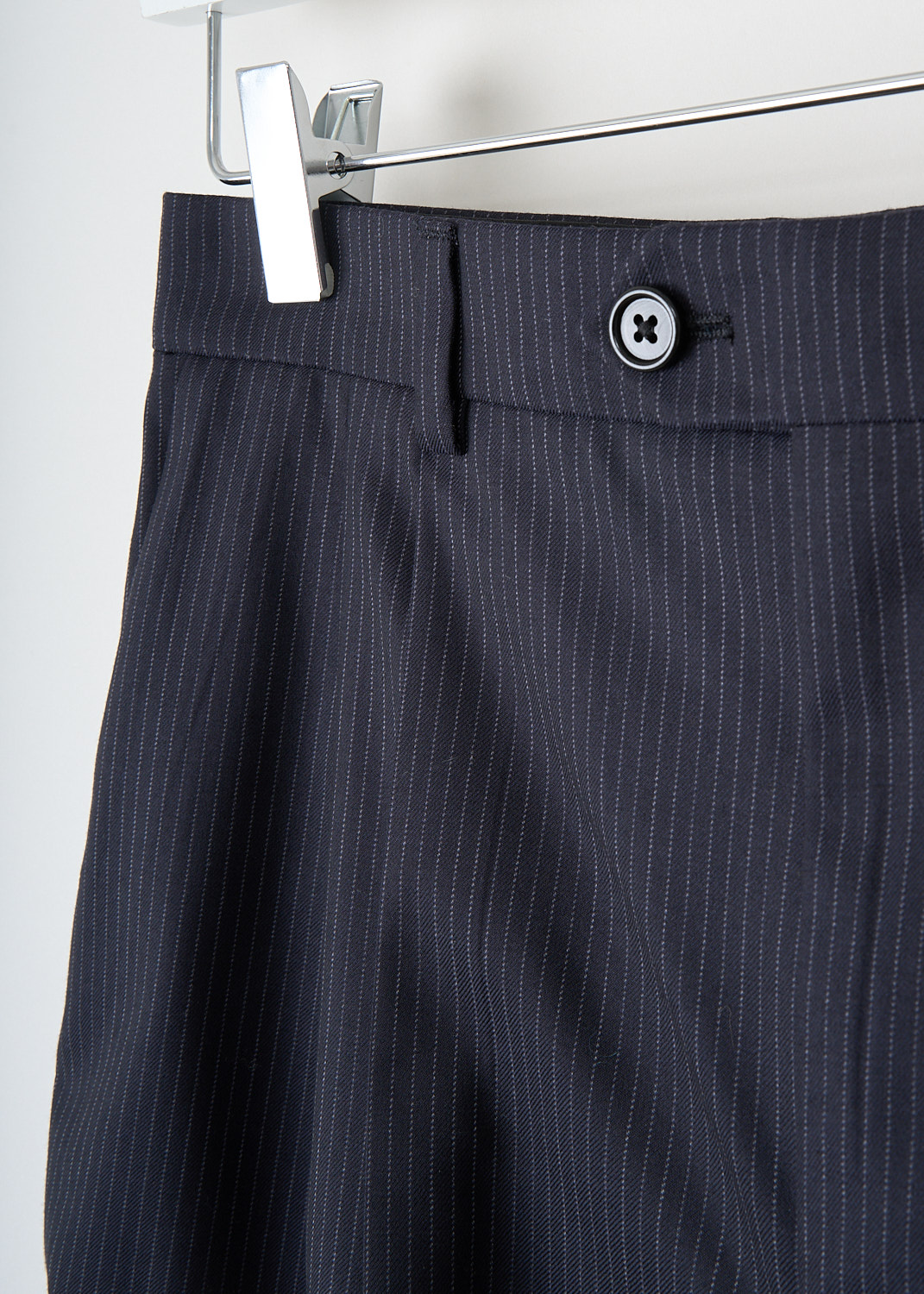 Close-up of navy blue pinstripe wool fabric and tailored waistband with belt loops and concealed closure on Celine high-waisted skate shorts.