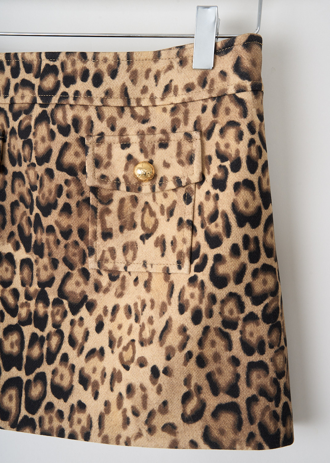 Close-up of front patch pockets with gold-tone buttons on Celine leopard print mini skirt in wool-cotton blend fabric.