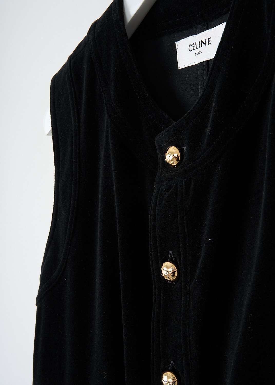 Close-up of gold-tone button front closure on Celine black velvet dress.