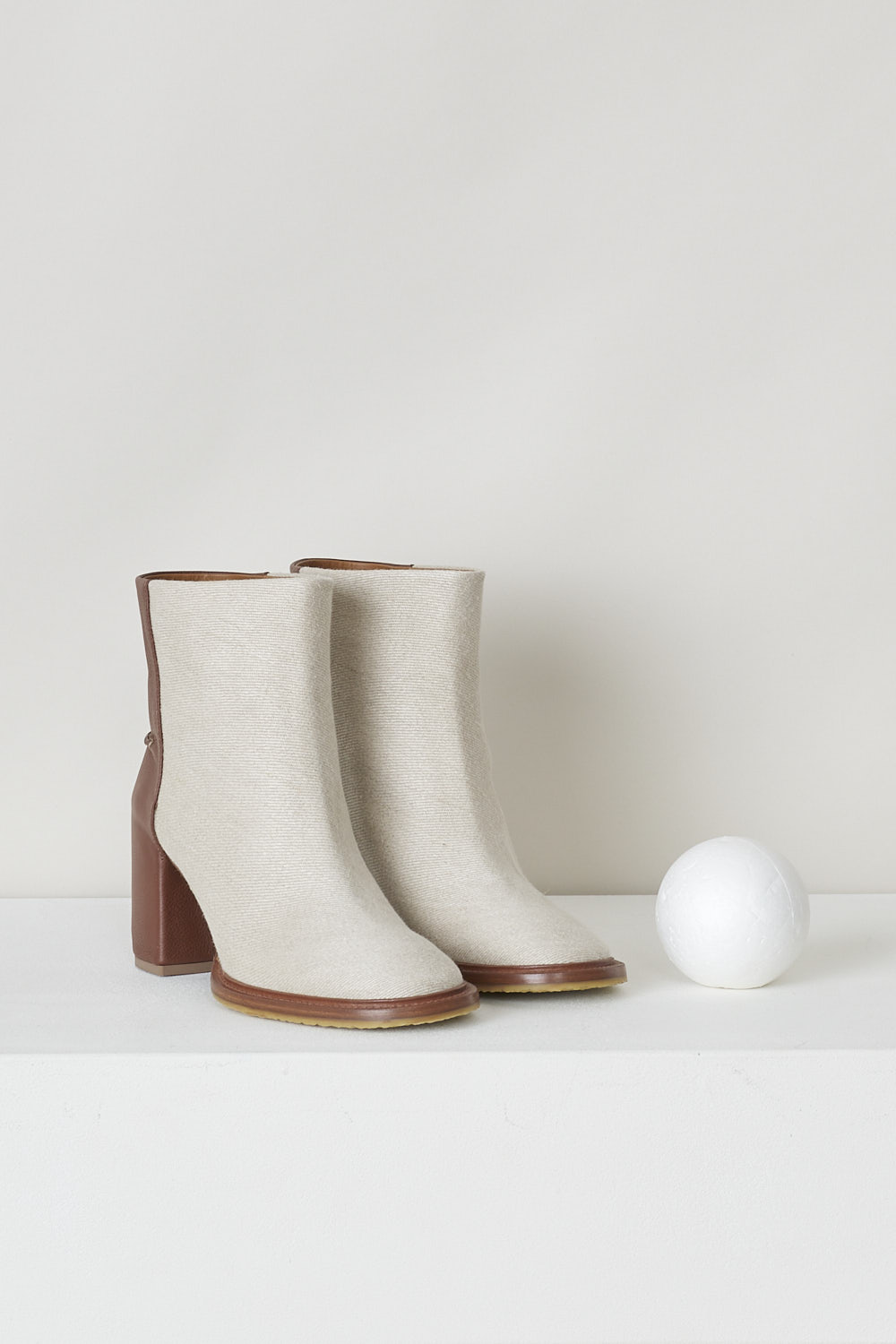 CHLOÃ‰, BEIGE EDITH ANKLE BOOT WITH BROWN HEEL, CHC22S521W89C, Beige, Brown, Front, These beige slip-on ankle boots have a brown leather-clad block heel with white stitching on the ankle. The boots have a round toe and a contrasting brown sole. 
