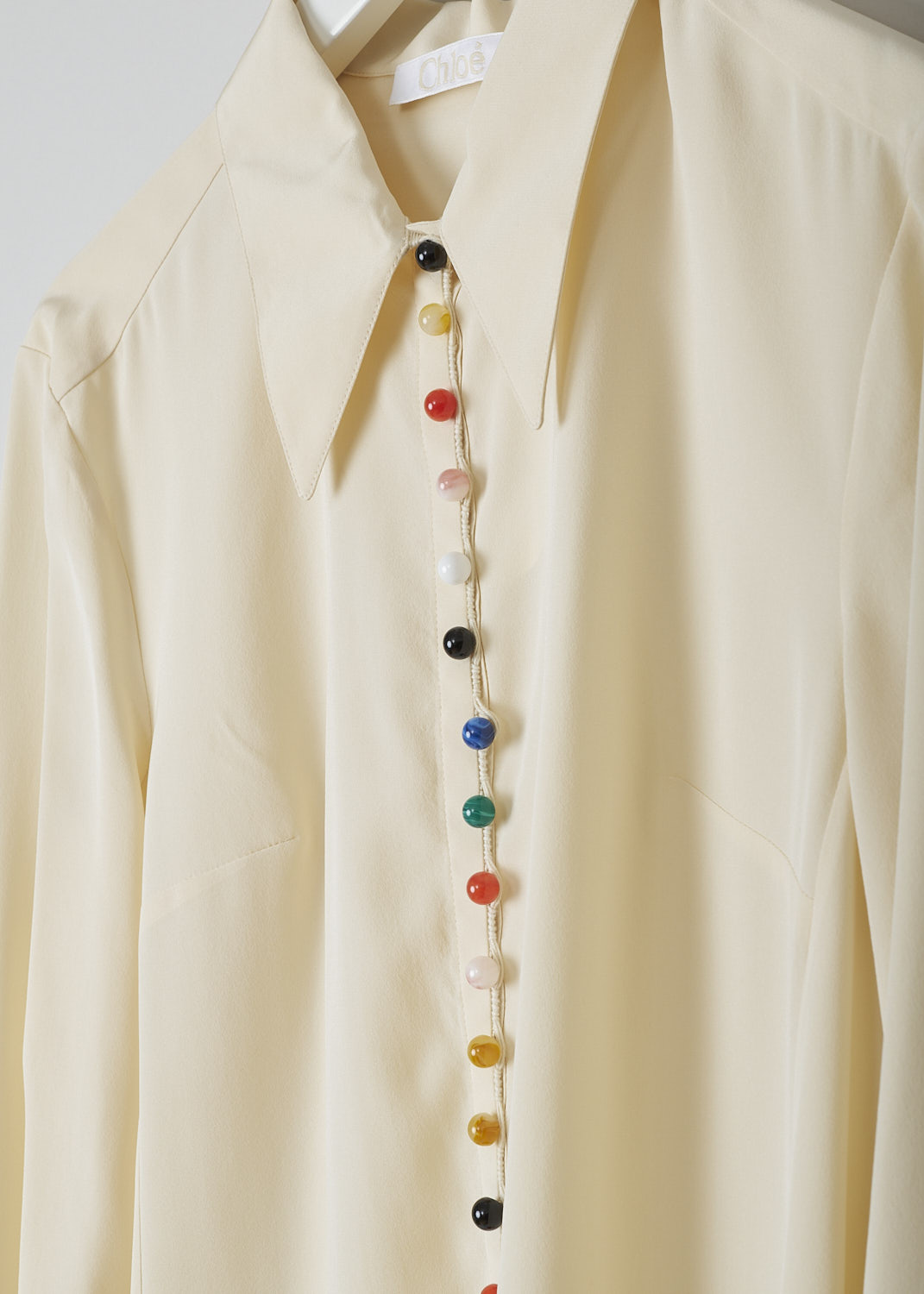 CHLOÉ, BEIGE BLOUSE WITH MULTICOLORED BEAD BUTTONS, CHC22SHT2900524T_SEED_PEARL_BEIGE, Beige, Detail, This light beige blouse features a pointed collar and has a front button closure with resin-based bead buttons in various colors. Those same bead buttons can be found on the cuffs. The blouse has a straight hem with a centre slit in the front. 
