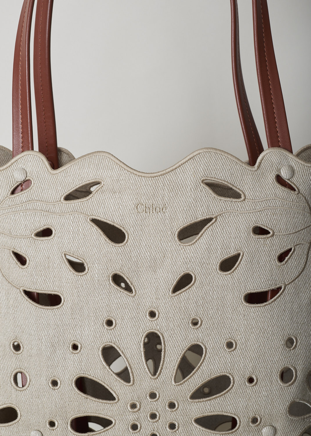 CHLOÃ‰ LARGE KAMILLA NORTH - SOUTH TOTE BAG IN SEPIA BROWN
,CHC22SS492G2327S_KAMILLA_LARGE_NORTH_SO, Beige, Detail, This large Kamilla North - South tote bag in sepia brown has two tan leather top handles. The linen has a scalloped top edge and floral broderie anglaise detailing throughout. On the inside, the bag has a removable tan leather pouch with a zipper.  