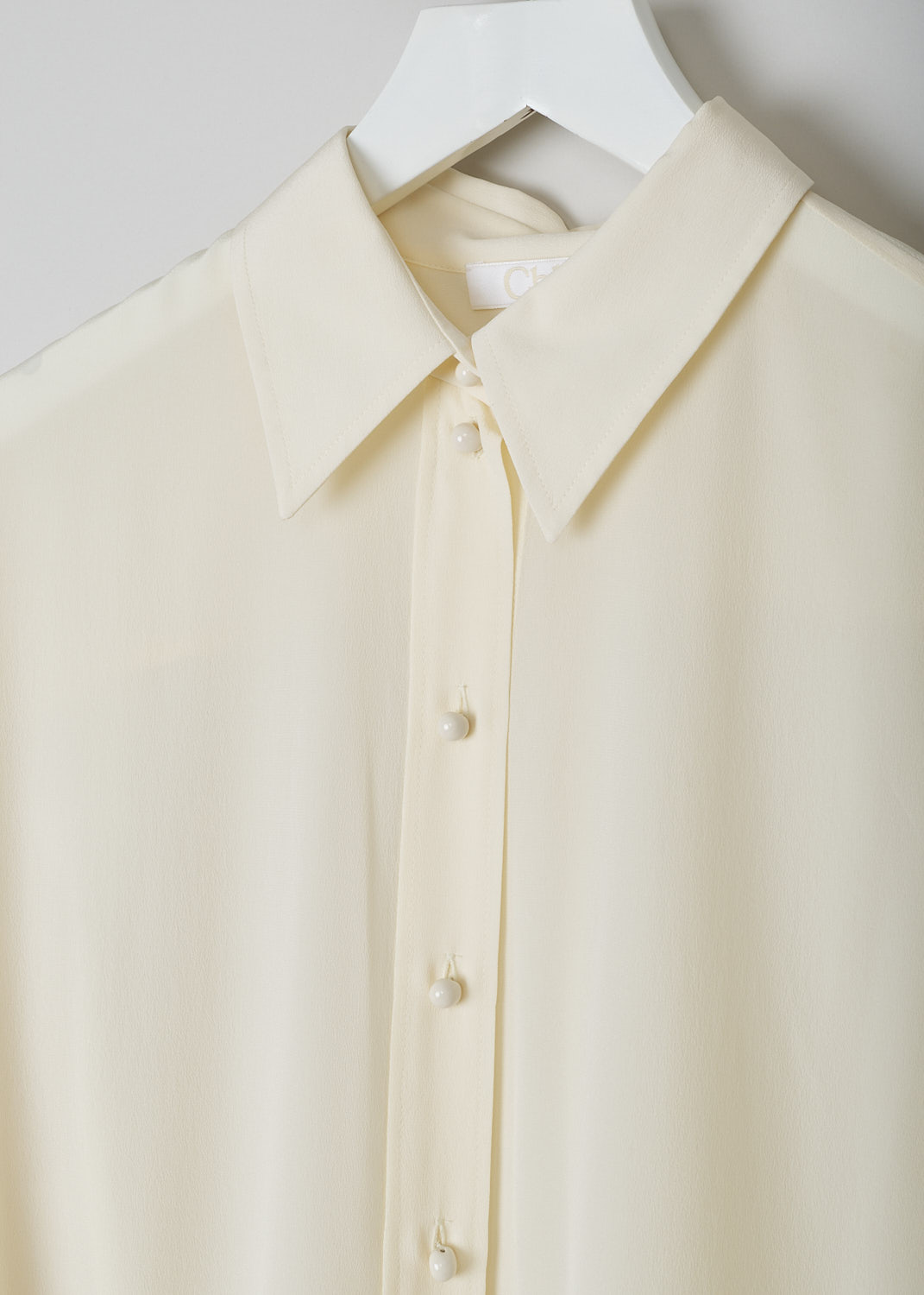 CHLOÉ, PRISTINE WHITE SILK BLOUSE, CHC22UHT05004114, White, Detail, This silk Pristine White blouse has a classic collar and a button placket with round ceramic. The blouse has long sleeves with buttoned cuffs.  A centre box pleat runs vertically down the back.
