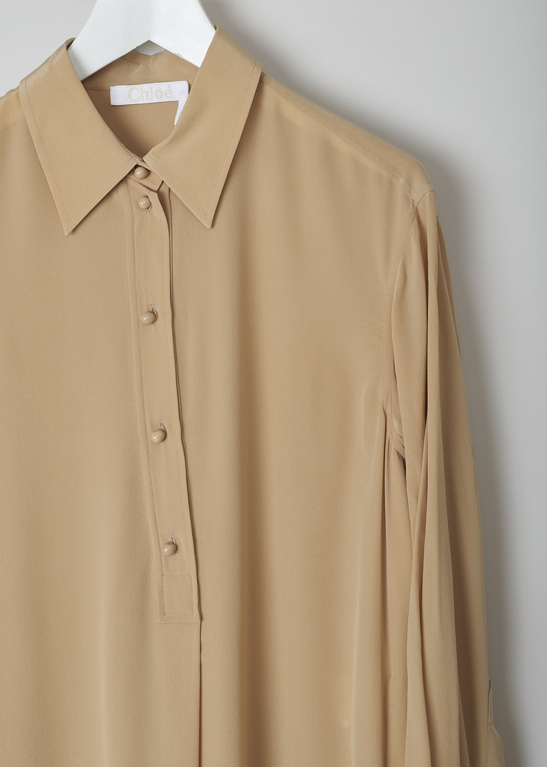 CHLOÉ, PEARL BEIGE SILK SHIRT DRESS, CHC22URO64004278, Beige, Detail, This pearl beige silk dress has a classic collar and a partial button placket with round ceramic buttons. Below the placket, a single knife pleats goes down to the hemline. This loose-fitted dress has long sleeves with buttoned cuffs. Slanted pockets are concealed in the side seam. The dress has side slits and an asymmetrical finish, meaning the back is a little longer than the front. A centre box pleat runs vertically down the back.