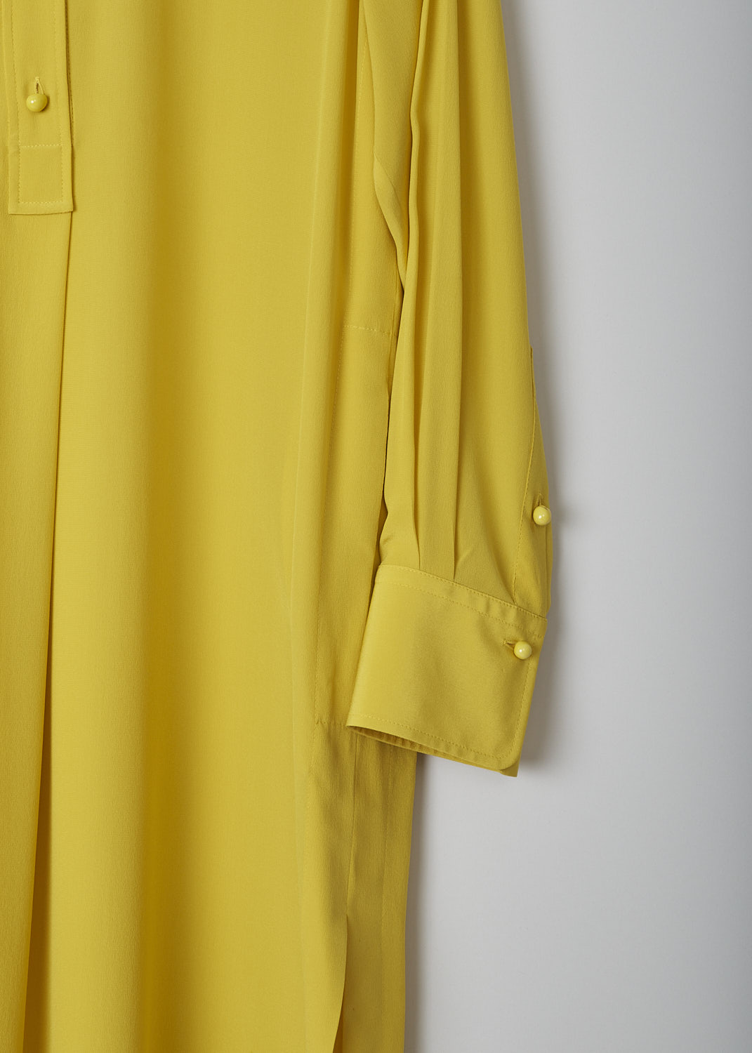 CHLOÃ‰, MUSTARD YELLOW DRESS, CHC22URO64004732_MUSTARD, Yellow, Detail 1, This mustard yellow shirt dress has a spread collar and a front button placket with ceramic buttons that reaches about halfway down. The long sleeves have cuffs with those same ceramic buttons. Slanted pockets are concealed in the side seam. The dress has a straight hemline with side slits. In the back, the dress has a centre box pleat. 
 
