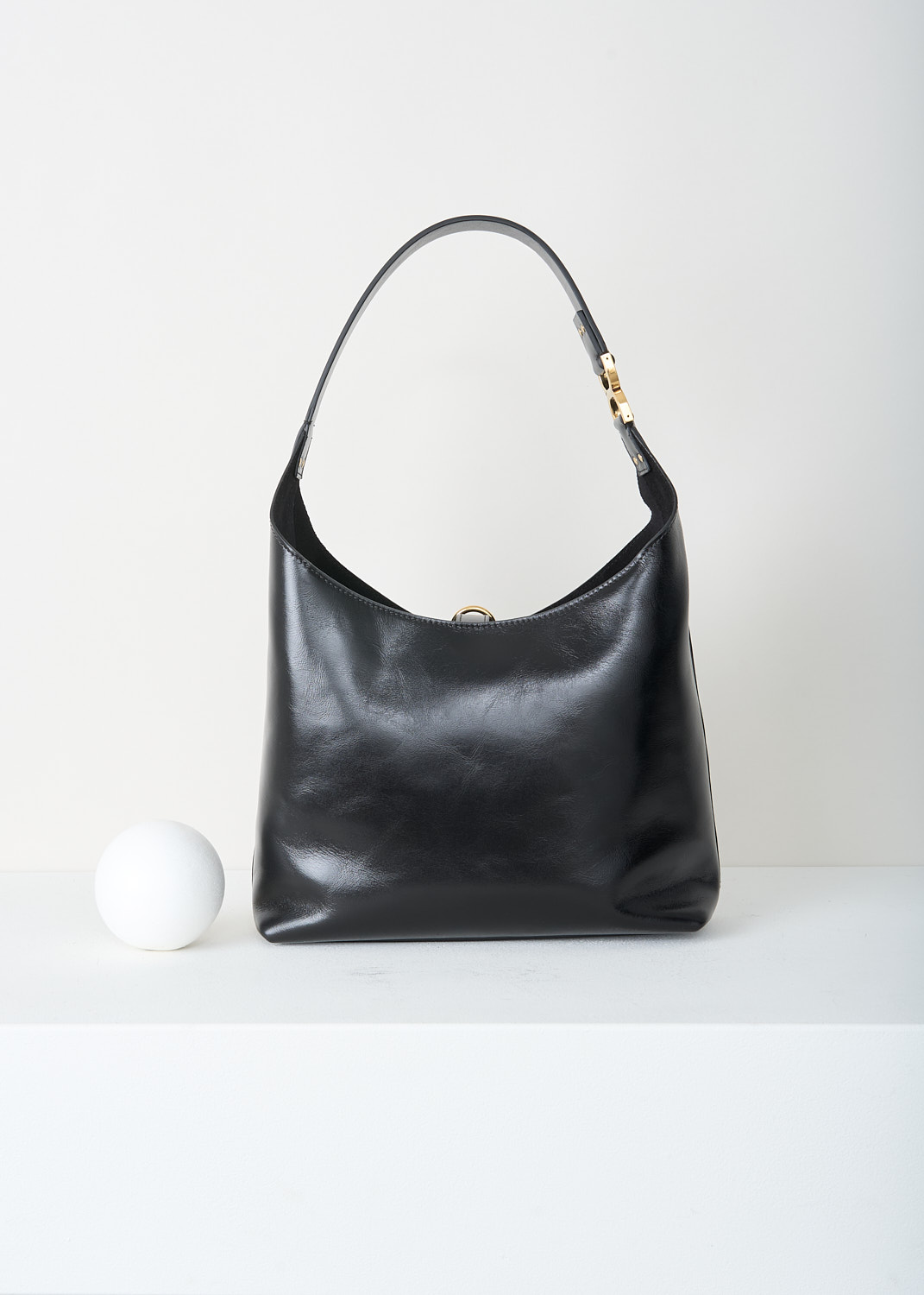 Chloé, Marcie tote bag in black, CHC24AS629N57_001_BLACK, Black, Back, This Marcie tote bag is made from supple black leather with a smooth, subtly glossy finish. It features a soft, slouchy, crescent-shaped silhouette and a single shoulder strap. Gold-tone hardware is used throughout. The bag closes with a vertical leather strap with small metal-tipped ends and a gold-tone O-ring at the top. Inside, the bag has a zipped slip pocket. 
