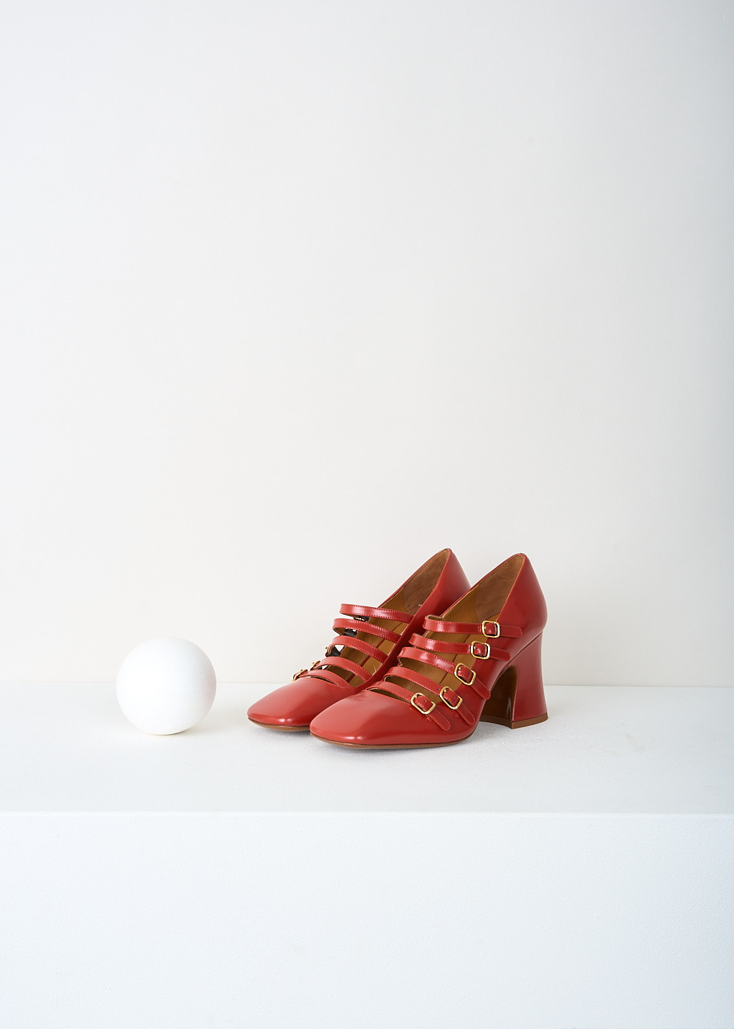 Chloé Janis pumps in earthy red glossed leather with squared toe, five vamp straps and gold-tone buckle, available at Kiki’s Stocksale designer outlet Maastricht.