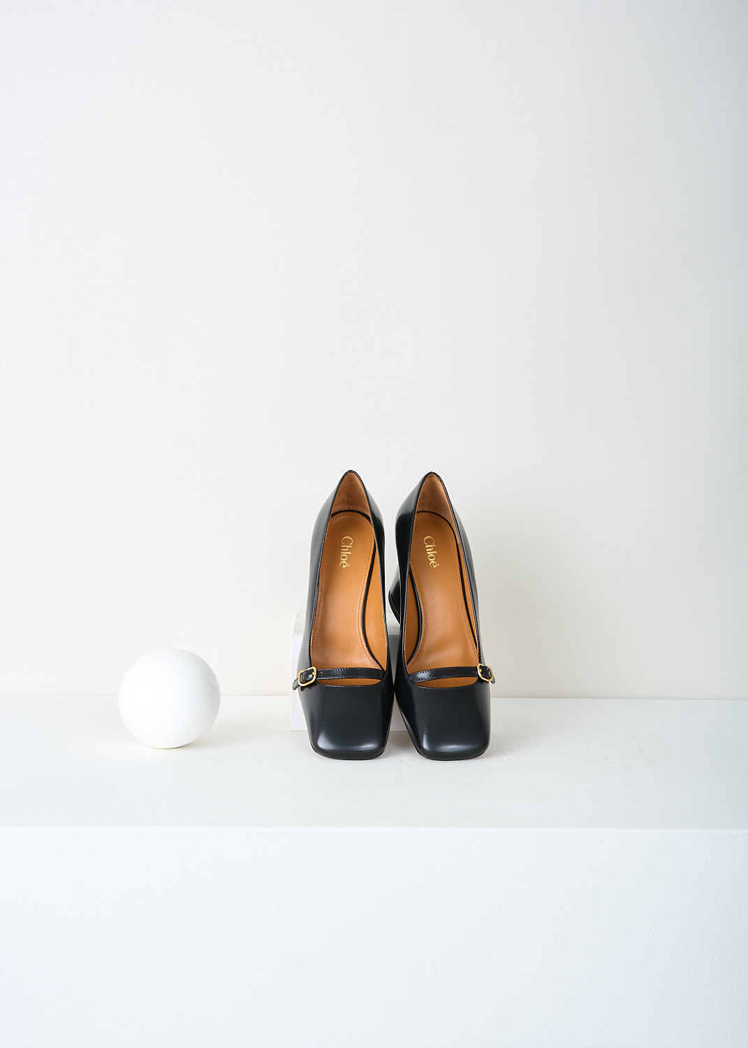 Top of squared toe and front strap with gold-tone buckle on Chloé Janis pumps.