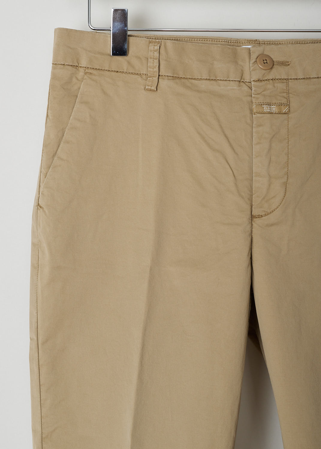 STEWART_C91796_53S_SR_919 CLOSED CLASSIC BEIGE TROUSERS Beige, Detail, These classic trousers in beige feature belt loops and a zipper and button closure. They feature slanted pockets on the front and two buttoned welt pockets on the back. What makes this model stand out the is the broad fold-over hem.
 