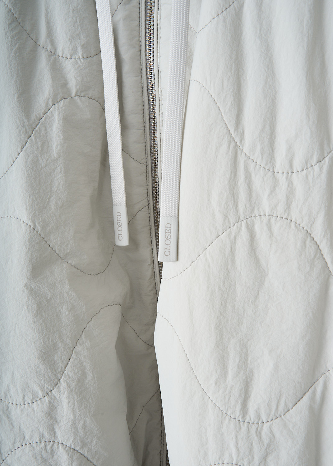 Close-up of matte quilted nylon fabric on Closed summer bomber jacket with dry finish and soft texture.