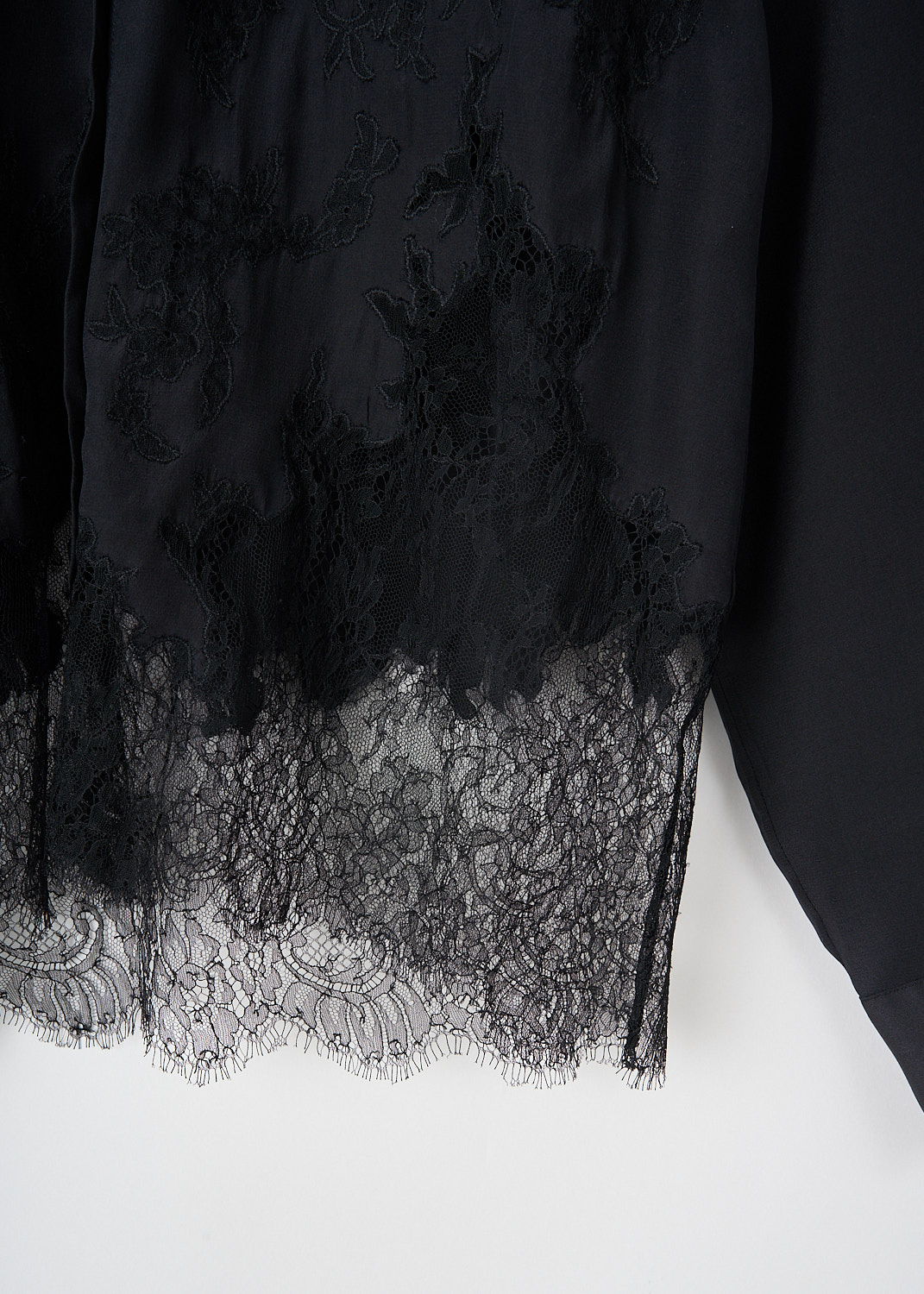 Close-up of black floral lace hem detail running up the front of Dries Van Noten silk blouse.