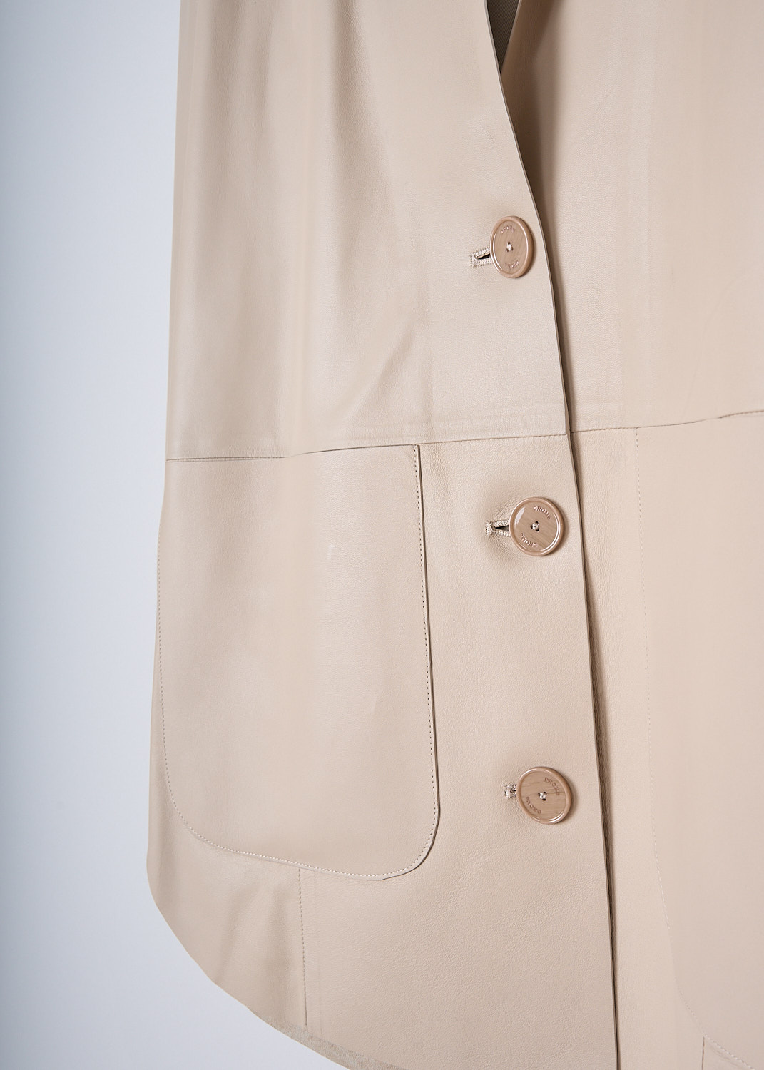 DROME, BOXY BEIGE LEATHER JACKET, DPD3112V_D400_B363, Beige, Detail, This single-breasted beige leather jacket has a notched lapel and a front button closure. The jacket has a boxy silhouette. On the front, the jacket has two patch pockets. The jacket has a rounded hemline. 
