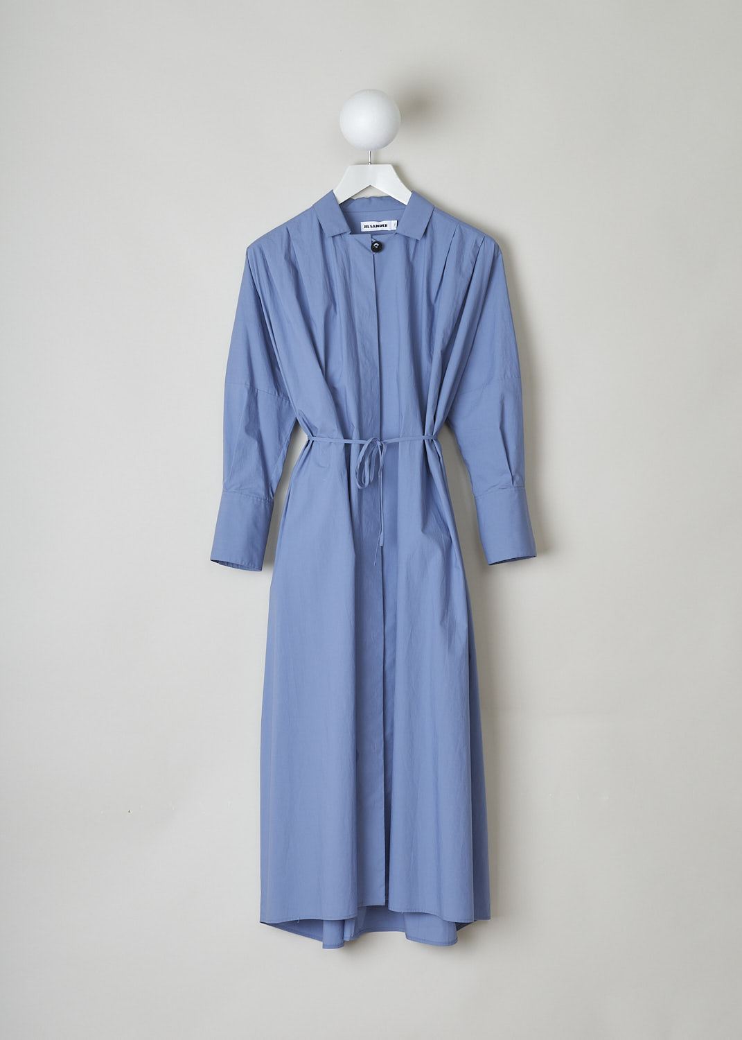 JIL SANDER, BLUE MIDI SHIRT DRESS WITH WAIST TIE, JSPO500806_WO242000_450, Blue, Front, This blue midi shirt dress has a spread collar with a straight neckline. The dress has a concealed front button closure with a single black button visible. The dress has three quarter sleeves with buttoned cuffs. The A-line silhouette can be cinched in with ties. Slanted pockets are concealed in the side seams. The dress has an asymmetrical finish, meaning the back is longer than the front.
