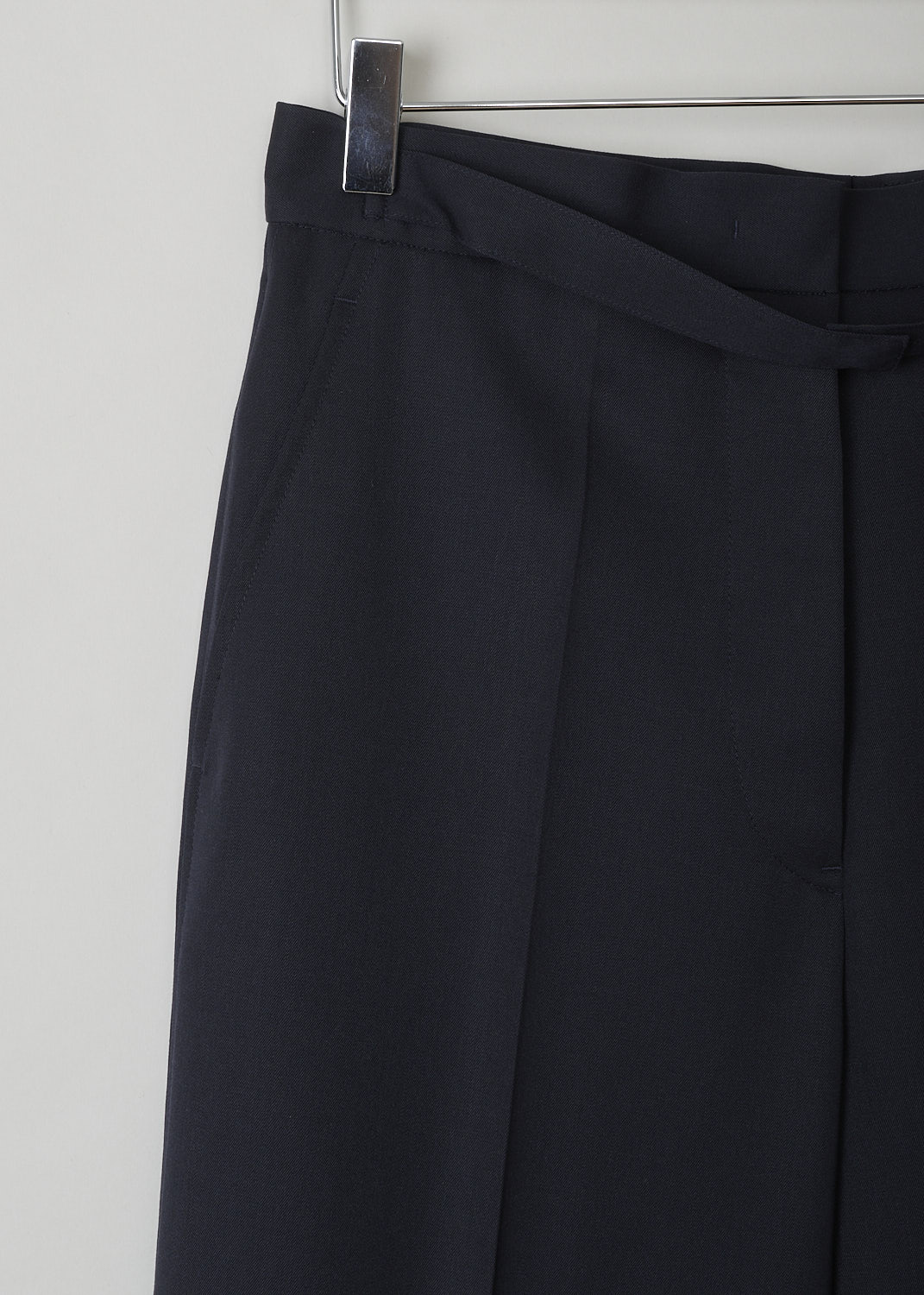 JIL SANDER, MIDNIGHT BLUE WIDE-LEG PANTS, JSPN302220_WN200300_402, Blue, Detail, These navy blue wool pants have a narrow waistband with, attached in the front, a narrow belt-like band with a concealed button closure. These pants have a concealed clasp and button closure. The wide pant legs have pressed creases. These pants have slanted pockets in the front and welt pockets in the back. 
