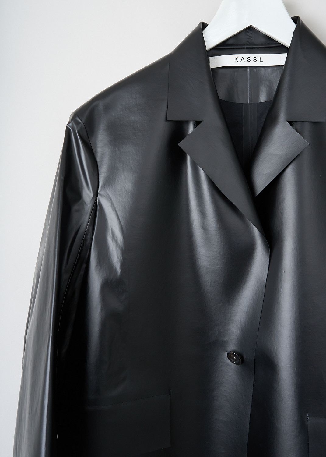 Close-up of single button closure on Kassl light black oil-coated cotton jacket, available at Kiki’s Stocksale Maastricht designer outlet.