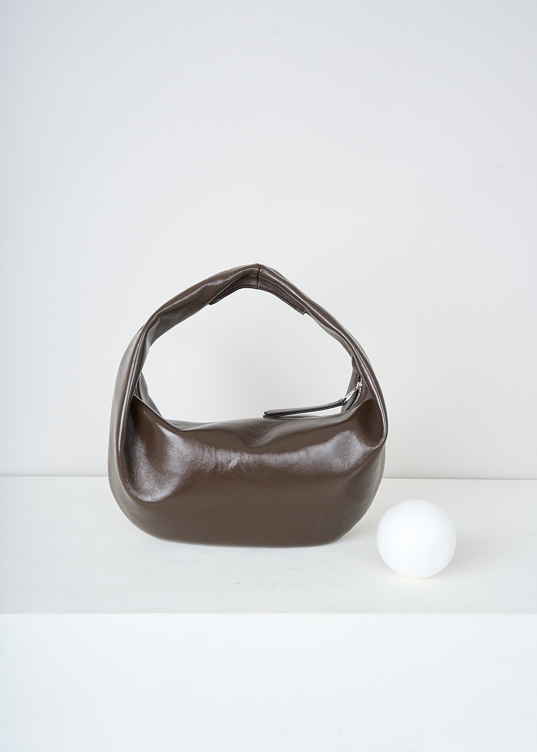 Khaite, Chestnut brown Olivia Hobo shoulder bag in medium, OLIVIA_HOBO_MEDIUM_H6015_877_934_CHESTNUT, Brown, Back, This medium Olivia Hobo shoulder bag in patent leather chestnut brown has a single top handle. The zipped top closure opens up to the main compartment with, to one side, a slip pocket. The bag has a curved silhouette. 
