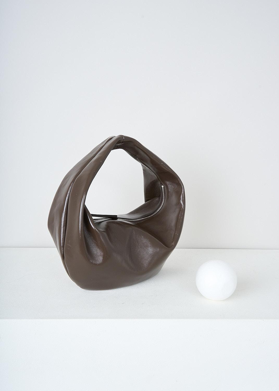 Khaite, Chestnut brown Olivia Hobo shoulder bag in medium, OLIVIA_HOBO_MEDIUM_H6015_877_934_CHESTNUT, Brown, Side, This medium Olivia Hobo shoulder bag in patent leather chestnut brown has a single top handle. The zipped top closure opens up to the main compartment with, to one side, a slip pocket. The bag has a curved silhouette. 
