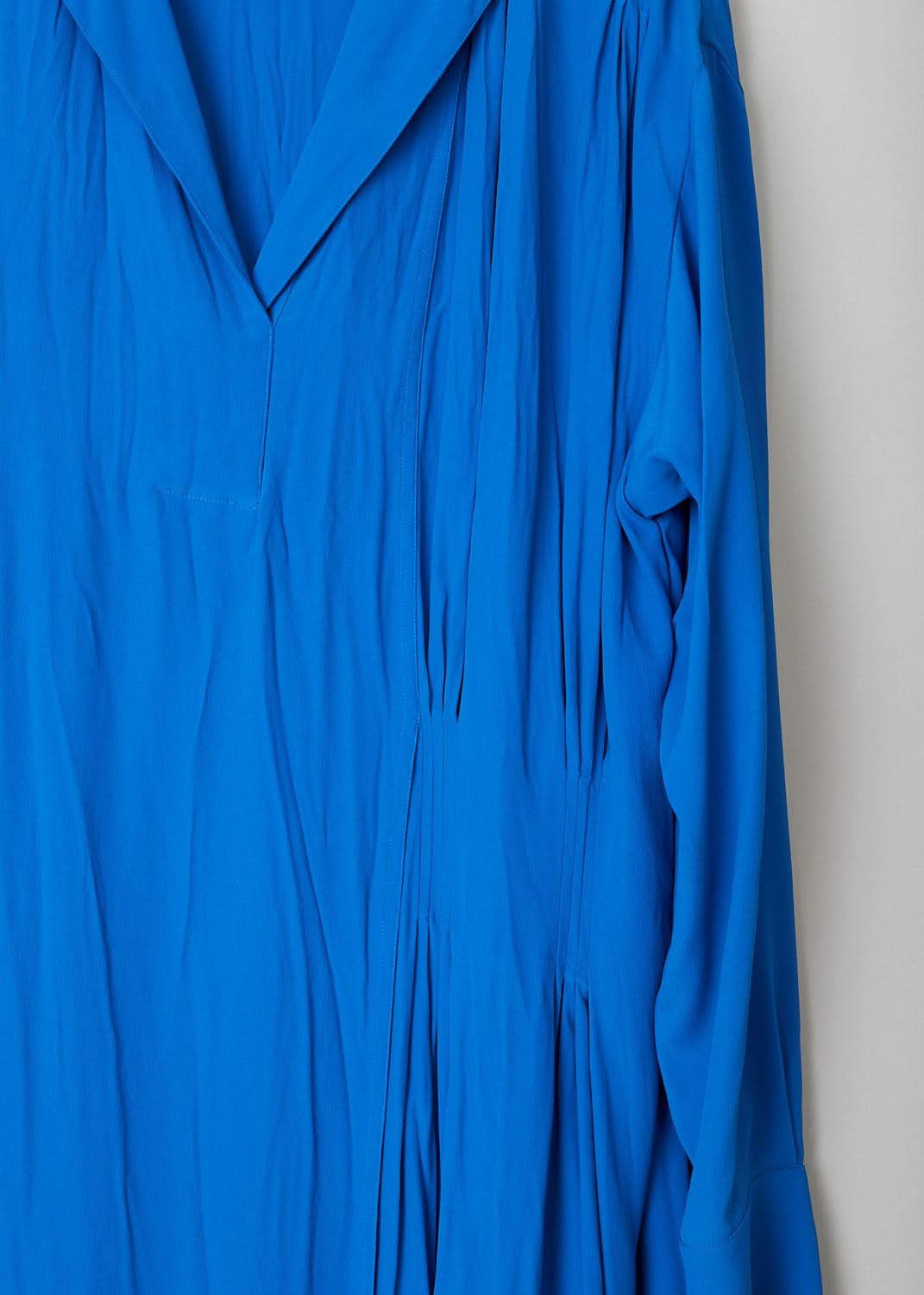 MARNI, ROYAL BLUE ASYMMETRICAL COLLAR DRESS, ABMA0171A0_TA089_00B57, Blue, Detail, The royal blue dress features a notched lapel and a split neckline. The long sleeves have buttoned cuffs. The dress is mid-length and has a wider fit. A pleated detail can be found on one side and the dress has a layered skirt. 
