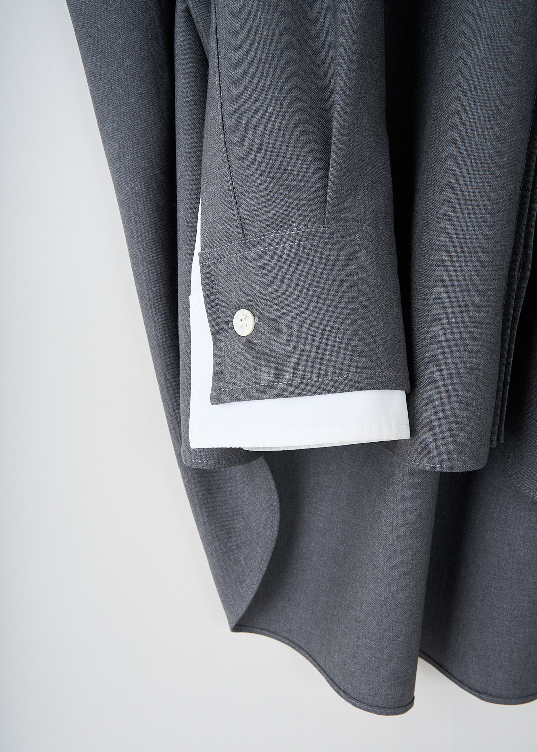 Close-up detail of Marni grey wool shirt showing embroidered logo, white layered sleeve detail and crystal pleat back yoke
