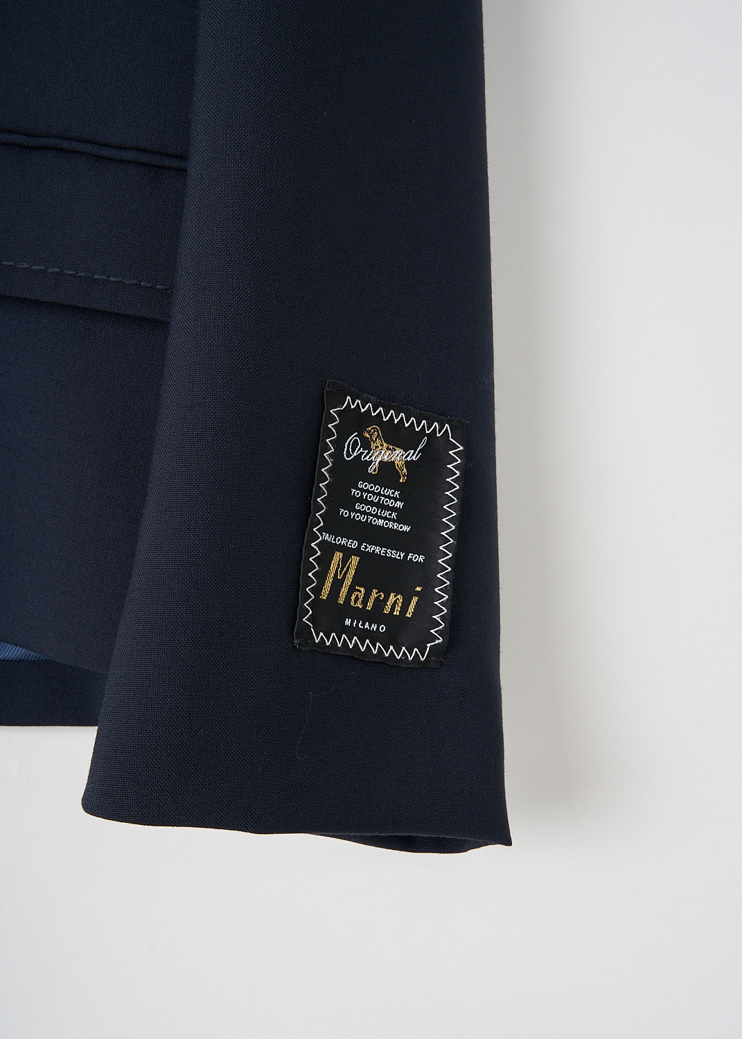 Close-up of sleeve with logo patch on dark blue wool Marni jacket, tailored designer outerwear with refined detailing.