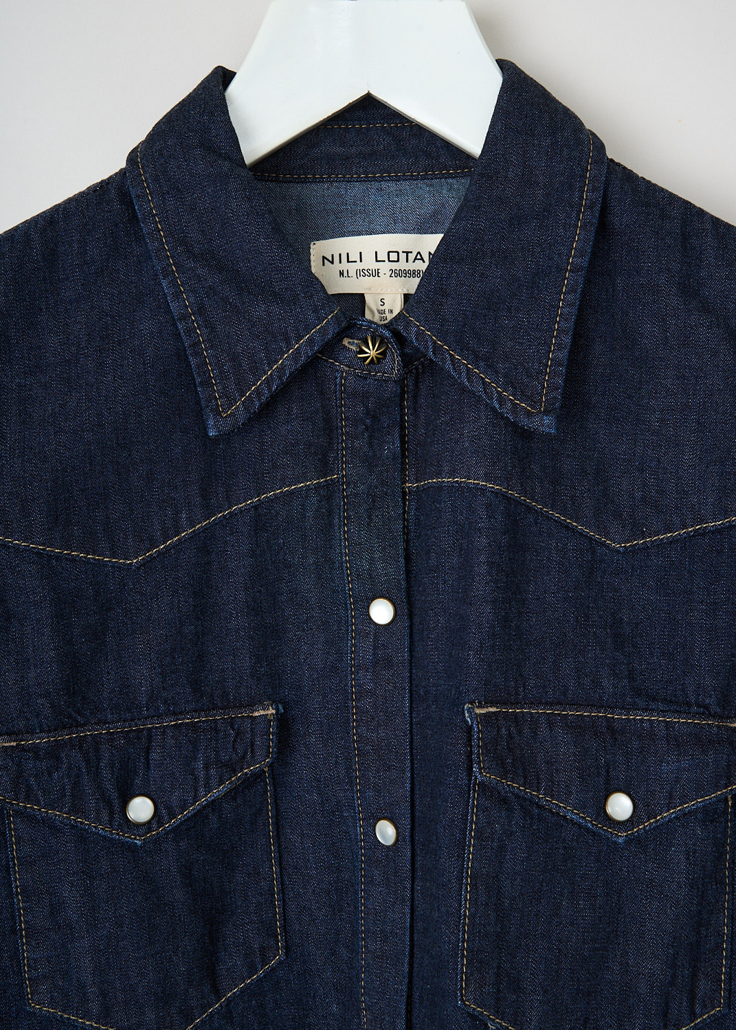 Close-up of the Nili Lotan Travis shirt showing mother-of-pearl press studs, classic collar and indigo denim fabric.