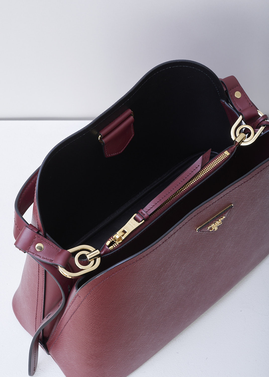PRADA, MEDIUM MATINÃ‰E SHOULDER BAG IN CHERRY RED, SAFFIANO_CUIR_C_1BA249_CERISE_NERO, Red, Detail 1, This cherry red MatinÃ©e shoulder bag is made with Saffiano leather. Both the leather handle and shoulder strap are adjustable and detachable. The bag has gold-tone metal hardware with the brand's triangle logo plaque on the front. The open top has a magnetic snap closure in the middle. The black interior has a centre zip pocket that divides the main compartment into two spacious sides. The bag has a removable leather keychain.  
 
