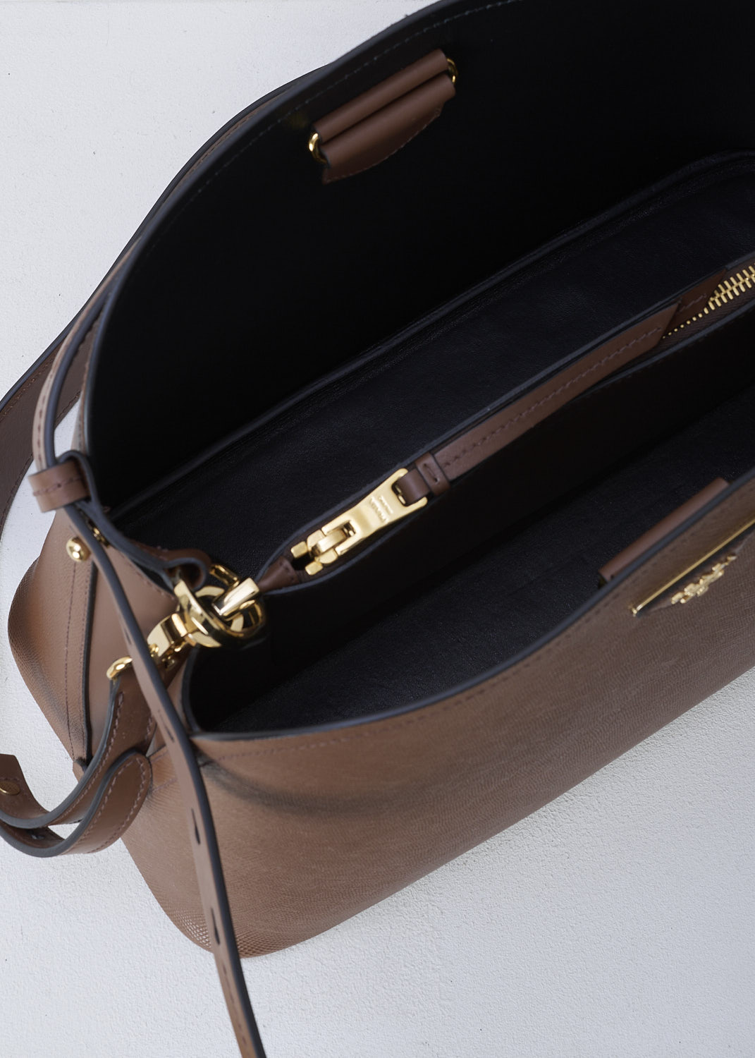 PRADA, MEDIUM MATINÃ‰E SHOULDER BAG IN BROWN, SAFFIANO_CUIR_C_1BA249_PALISSANDRO_NERO, Brown, Detail 1, This brown MatinÃ©e shoulder bag is made with Saffiano leather. Both the leather handle and shoulder strap are adjustable and detachable. The bag has gold-tone metal hardware with the brand's triangle logo plaque on the front. The open top has a magnetic snap closure in the middle. The black interior has a centre zip pocket that divides the main compartment into two spacious sides. The bag has a removable leather keychain.  



