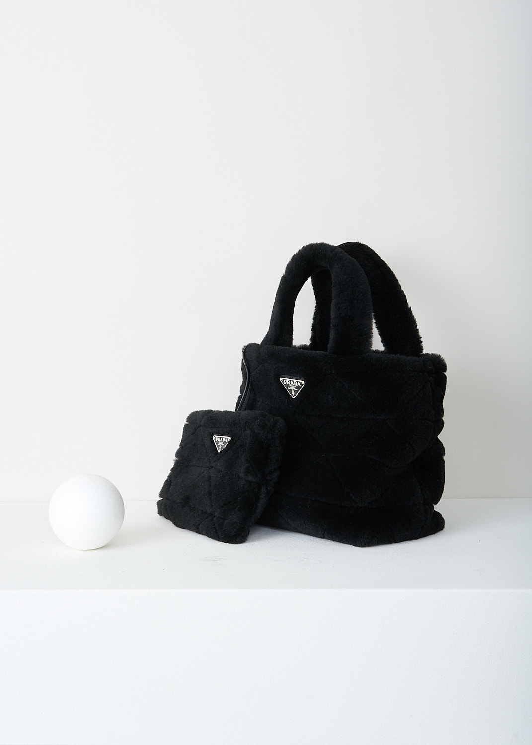 Prada, Black shearling shopper, 2EC9_MONTONE_1BG378_F0002_NERO, Black, Side, This plush black shearling tote bag has padded top handles and the signature quilted detailing. This bag has the brand's triangle logo in silver-tone hardware. The bag comes with a detachable shoulder strap and matching shearling pouch. 
