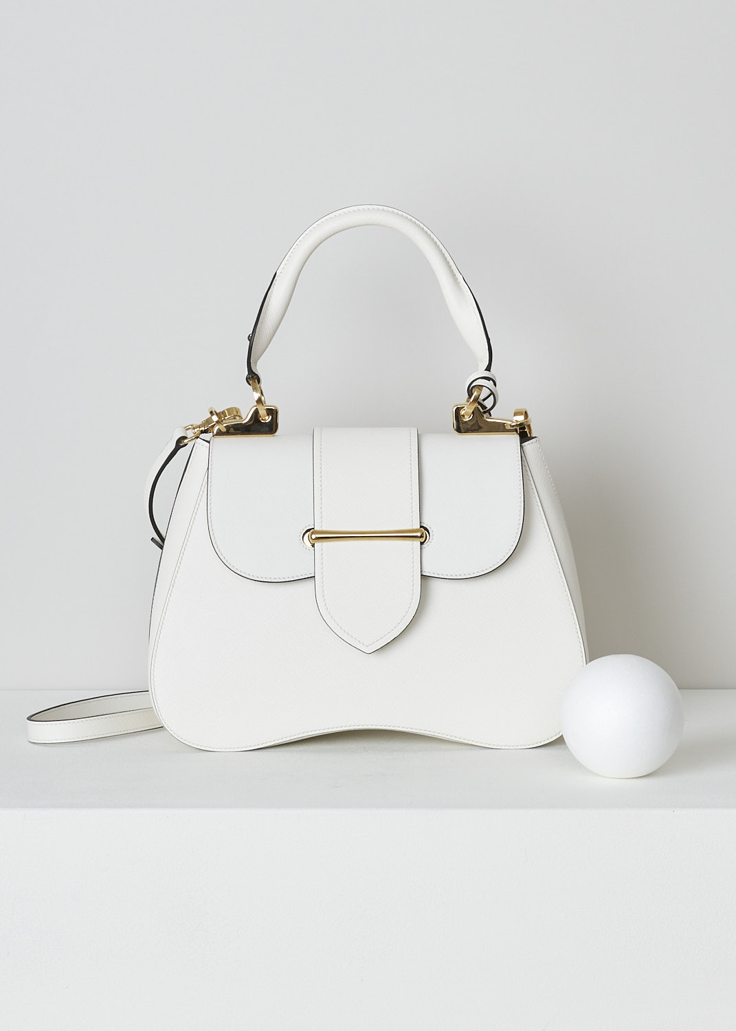 PRADA, MEDIUM SIDONIE TOP HANDLE BAG IN WHITE, CARTELLA_1BN005_F0009_BIANCO, White, Front, This mid-sized white Sidonie Top Handle Bag is made with Saffiano leather. The bag comes with a leather handle and an adjustable and detachable shoulder strap. The bag has gold-tone metal hardware with the brand's logo on the back. The removable leather keychain has that same gold-tone logo on it. The slip-through closure opens up to reveal its black interior. The bag has a single, spacious compartment with a zipped inner pocket to one side and a patch pocket on the other side.  
