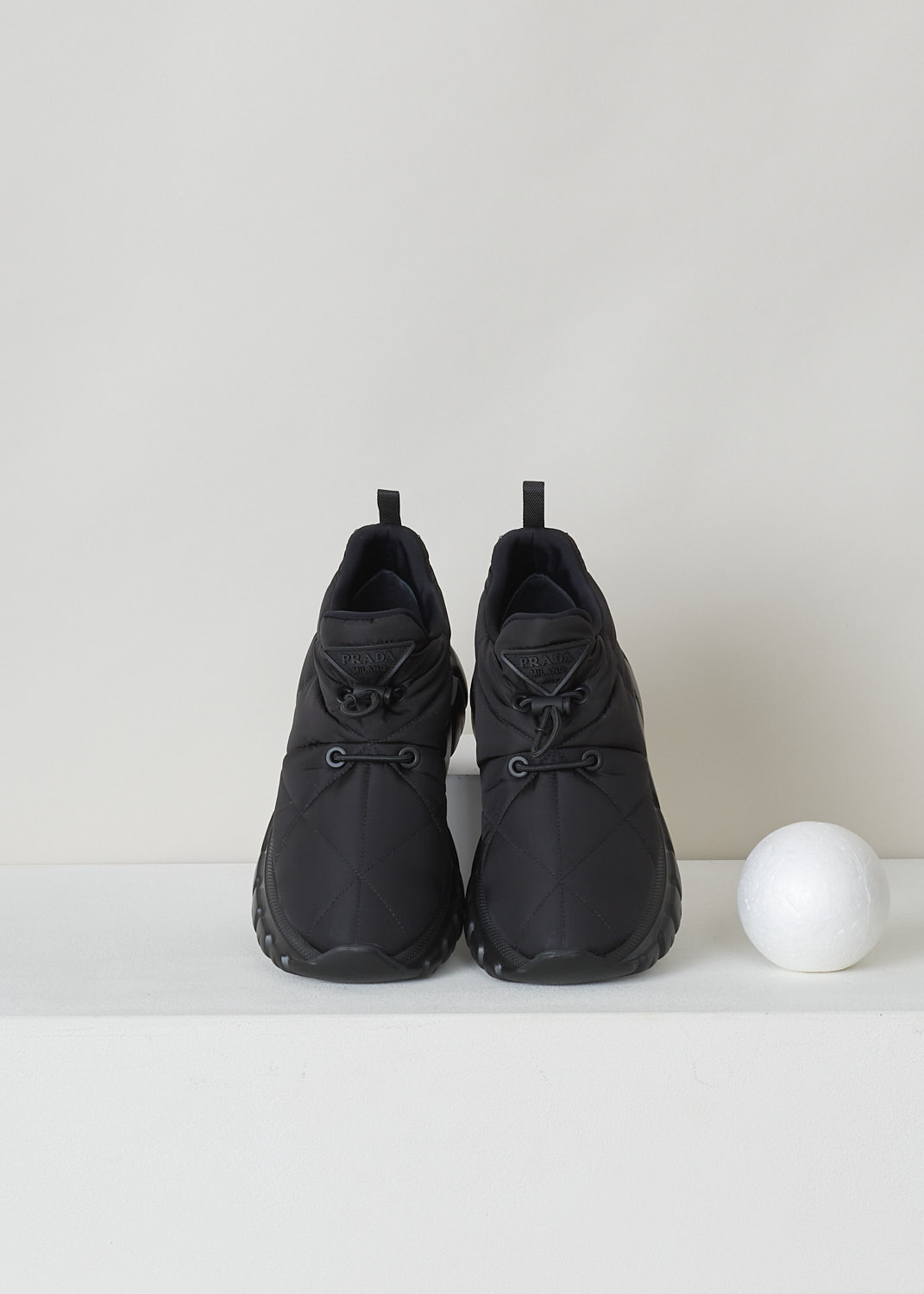 PRADA, BLACK PADDED NYLON SNEAKERS, 1E741M_3LGO_F0002_NYLON_PIUMA_NERO, Black, Top, These black padded slip-on shoes feature the brand's triangle logo in black on the front above the toggle fastening. The shoes have ribbed rubber soles.

