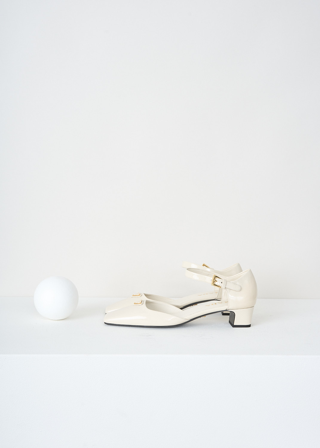 Prada, Patent leather off-white pumps with ankle strap, 069_VERNICE_1I601N_F0304_AVORIO, White, Side, These off-white patent leather Mary Jane pumps feature a squared-off toe with the brand’s signature triangle logo, a small block heel, and an ankle strap secured with a gold-tone buckle.

heel height: 3.5 cm / 1.3 in.
