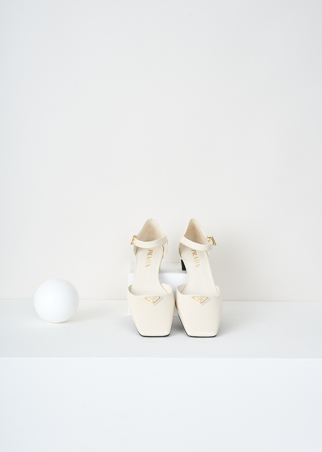 Prada, Patent leather off-white pumps with ankle strap, 069_VERNICE_1I601N_F0304_AVORIO, White, Top, These off-white patent leather Mary Jane pumps feature a squared-off toe with the brand’s signature triangle logo, a small block heel, and an ankle strap secured with a gold-tone buckle.

heel height: 3.5 cm / 1.3 in.
