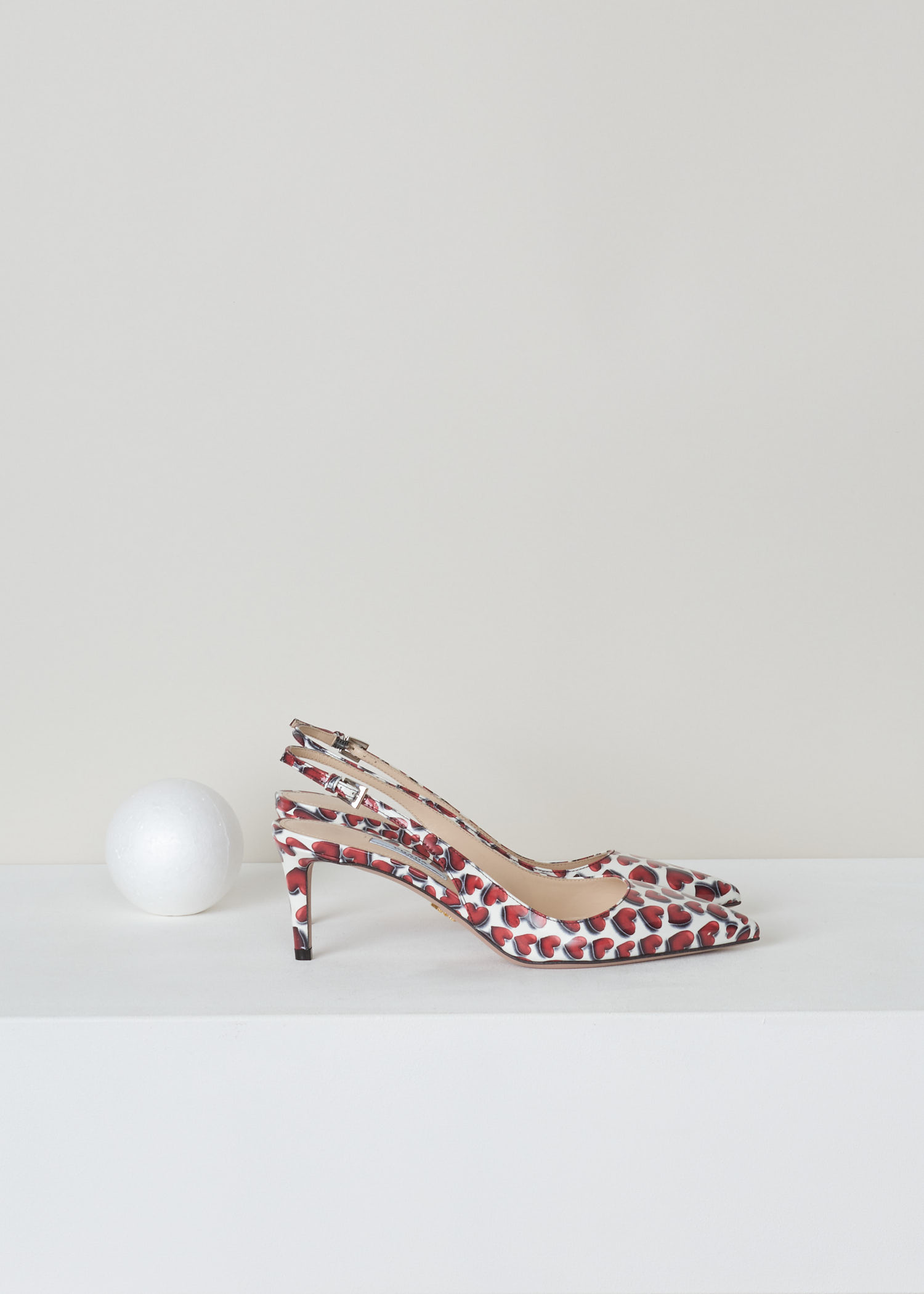 Prada, Red and white patent leather heart print, vernice_cuori_1I833I_F0D56_scarlatto, red white, side, Red and white heart printed slingback. Pointed toe and mid high stiletto heel. With a gold-tone logo plaque on the sole.